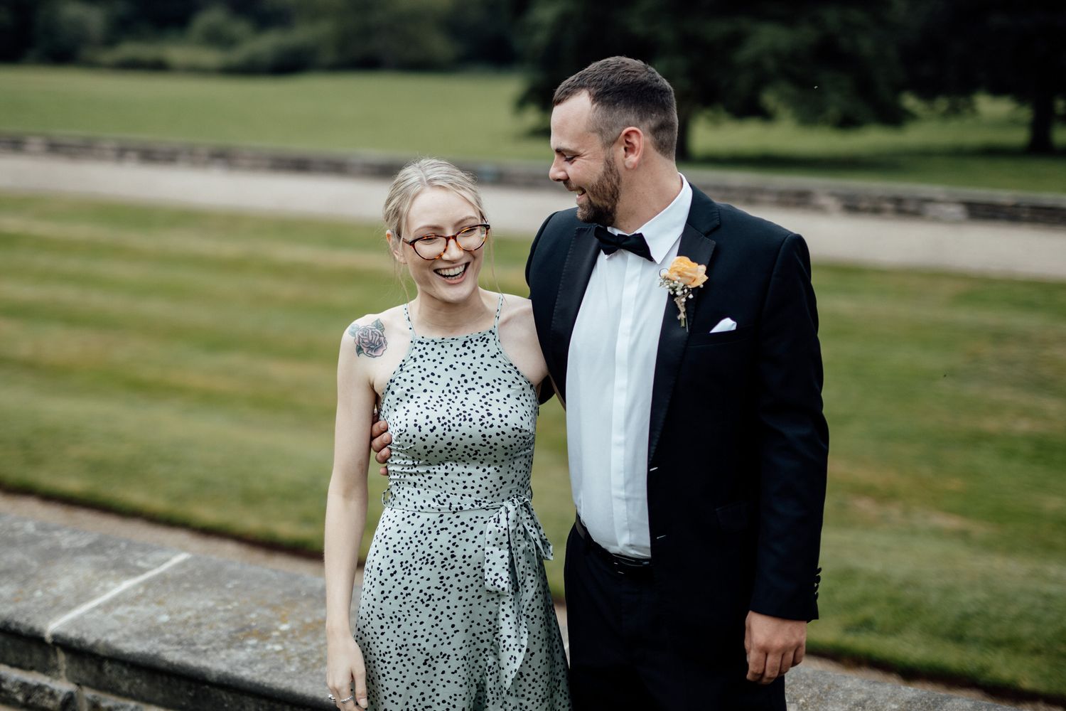 Wedding couple walking together outdoors in formal attire on a sunny day.