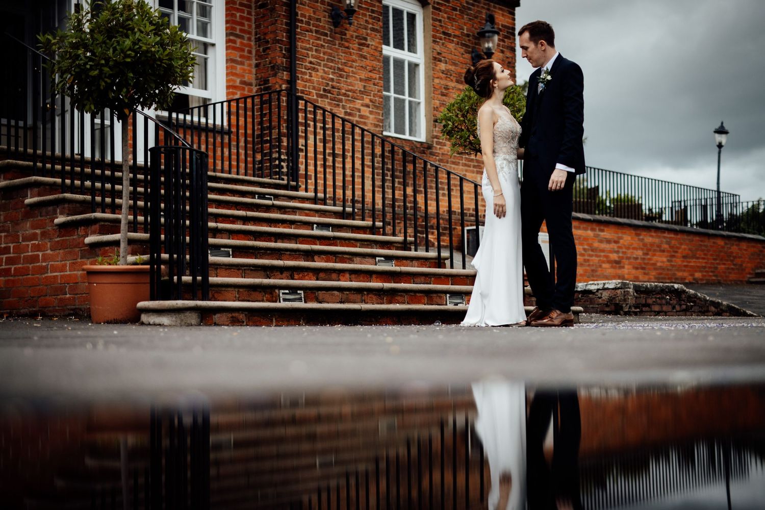 Dramatic wedding photos at brick building with stairs and iron railings.
