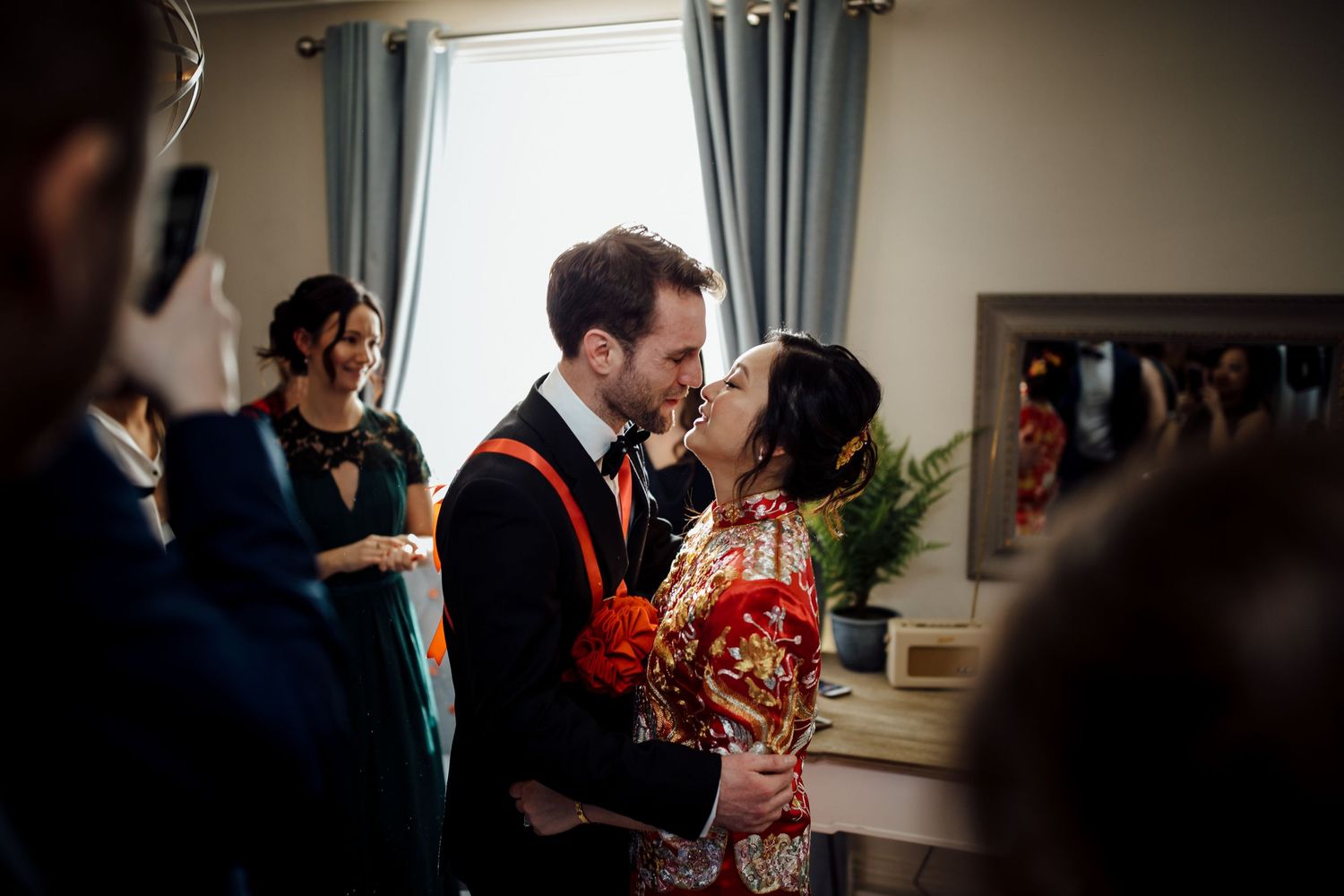 Intimate gathering in sunlit room with guests mingling at formal event.