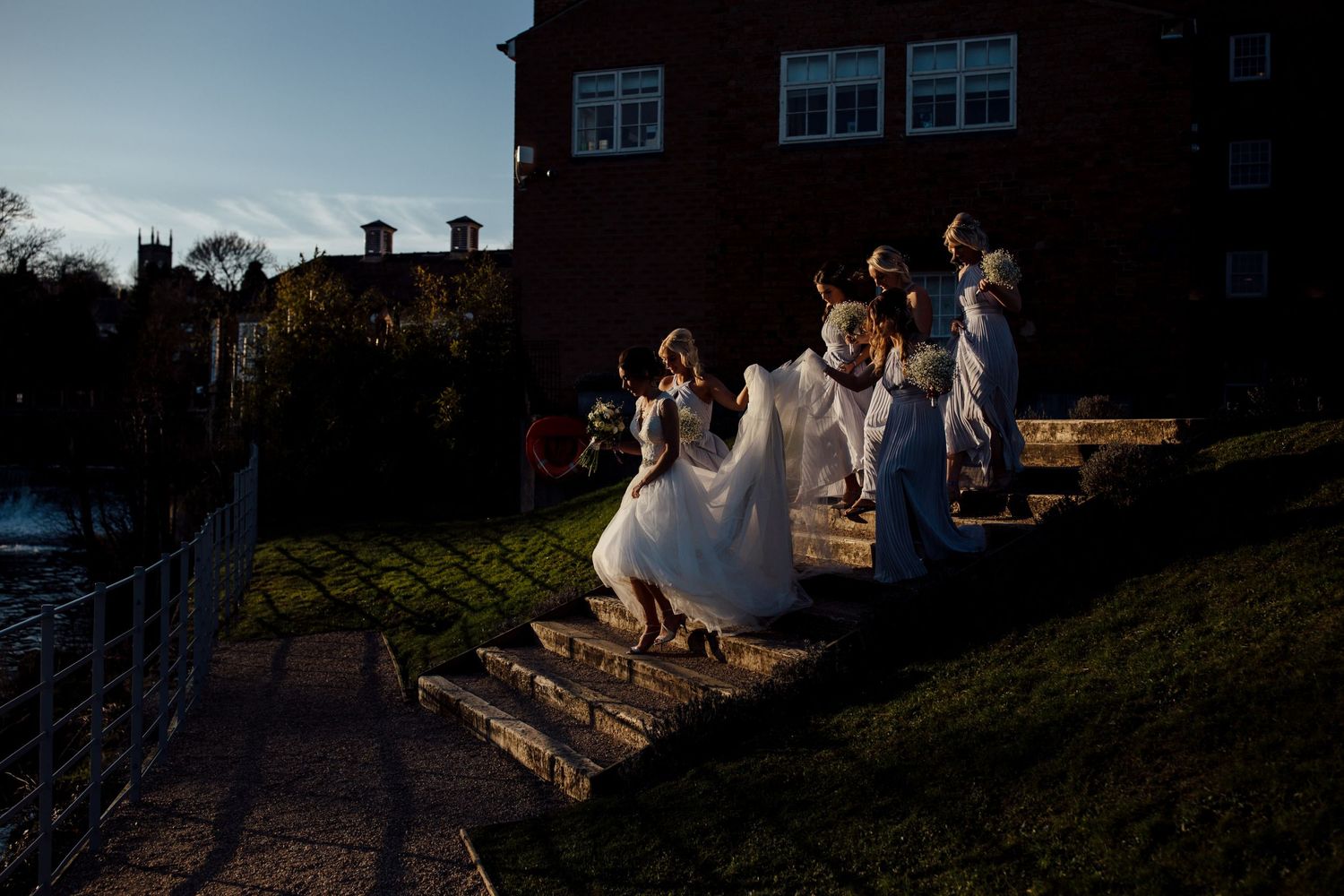 Wedding party poses outside a brick building during golden hour.