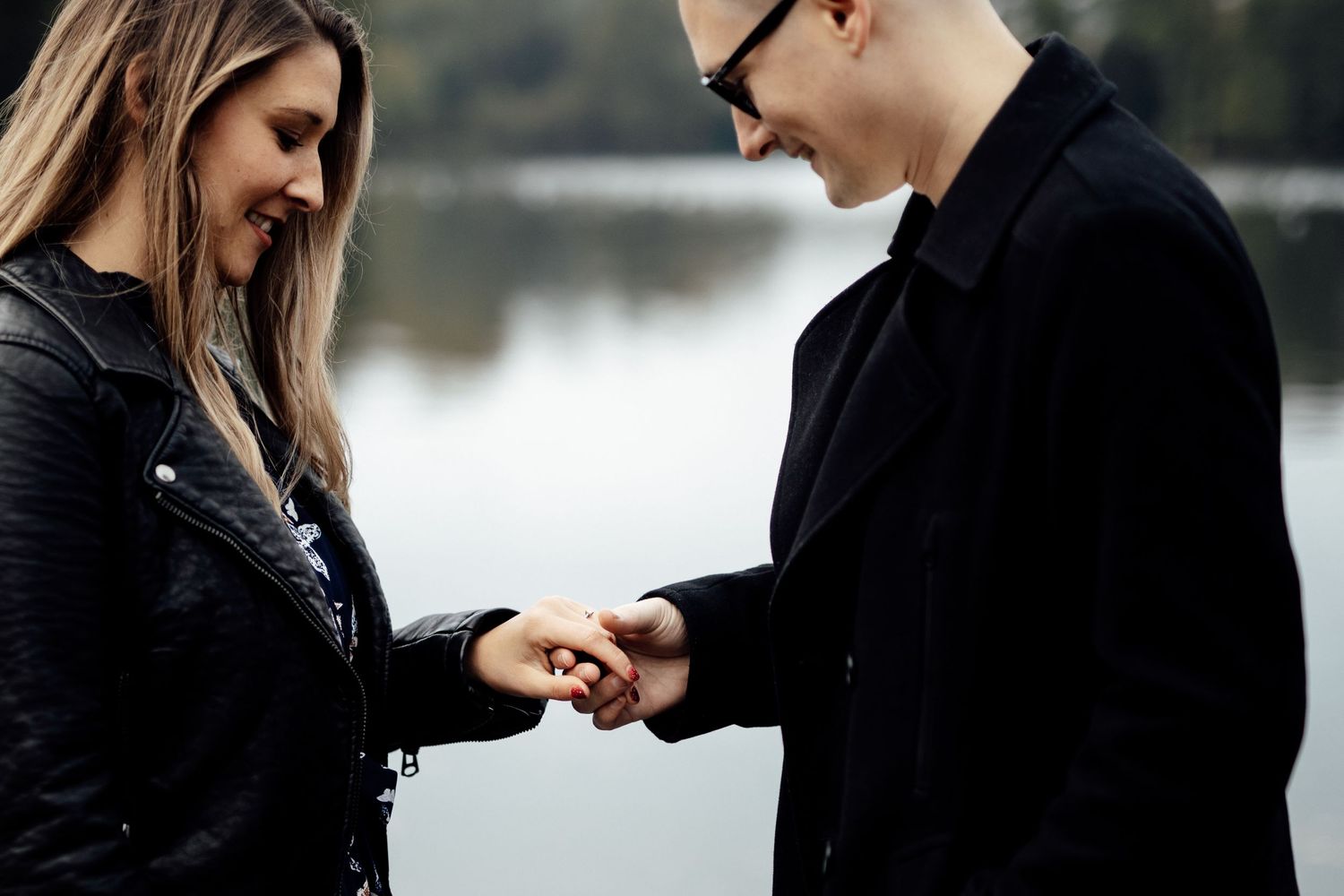 Couple shares intimate moment by tranquil waterfront setting.