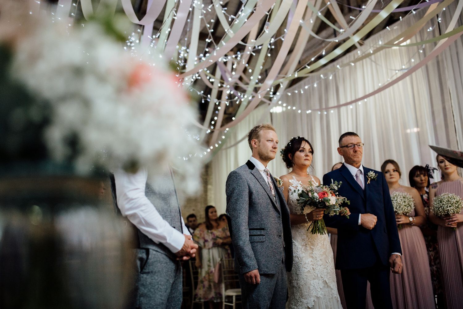 Wedding ceremony under crystal chandeliers and draped fabric.