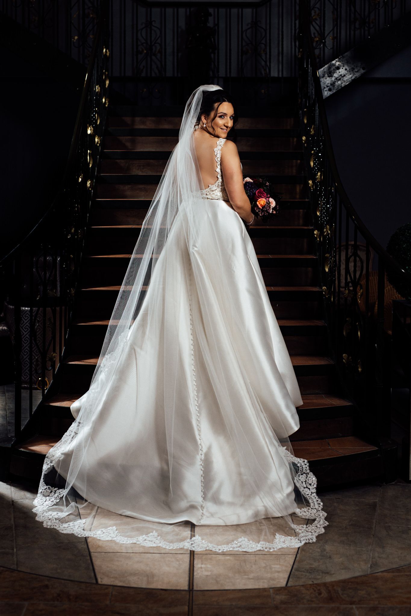 Dramatic shots of a flowing white wedding dress with lace details on stairs.