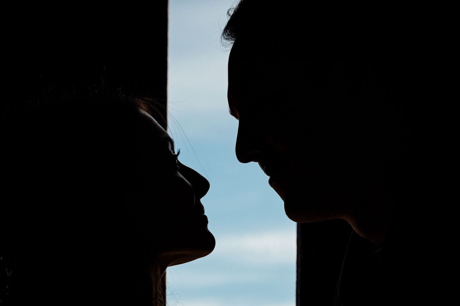 Silhouettes of two people standing close together against a dark background.