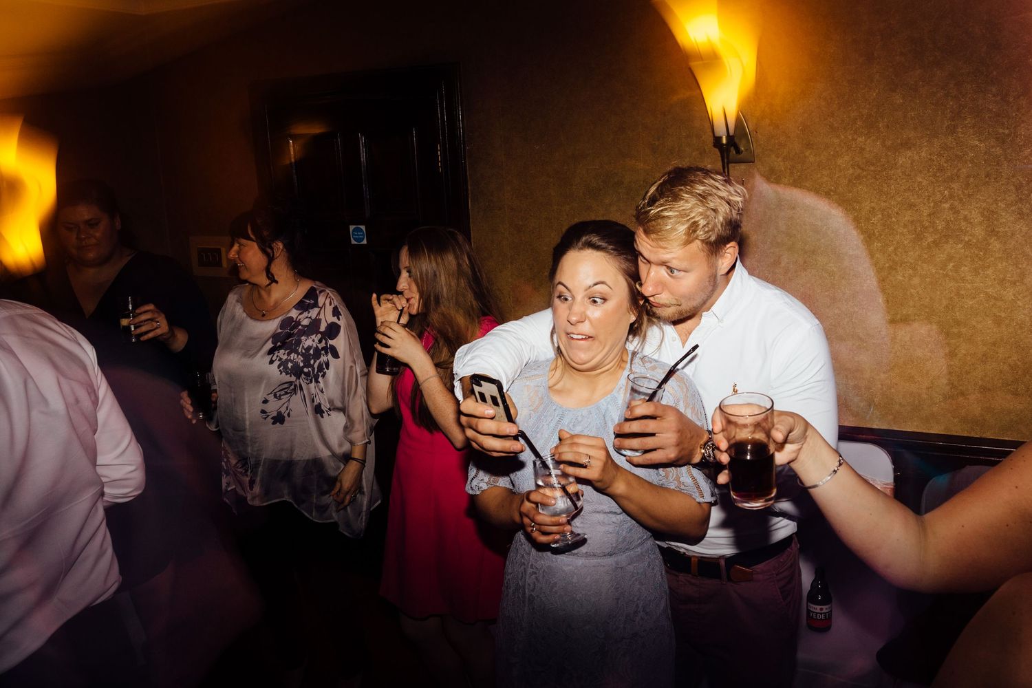 Warm-lit reception venue with guests enjoying evening celebrations.
