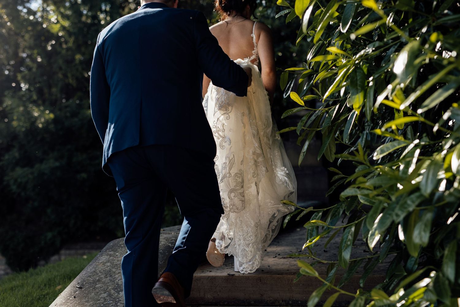 Wedding couple shares intimate moments among lush garden foliage.