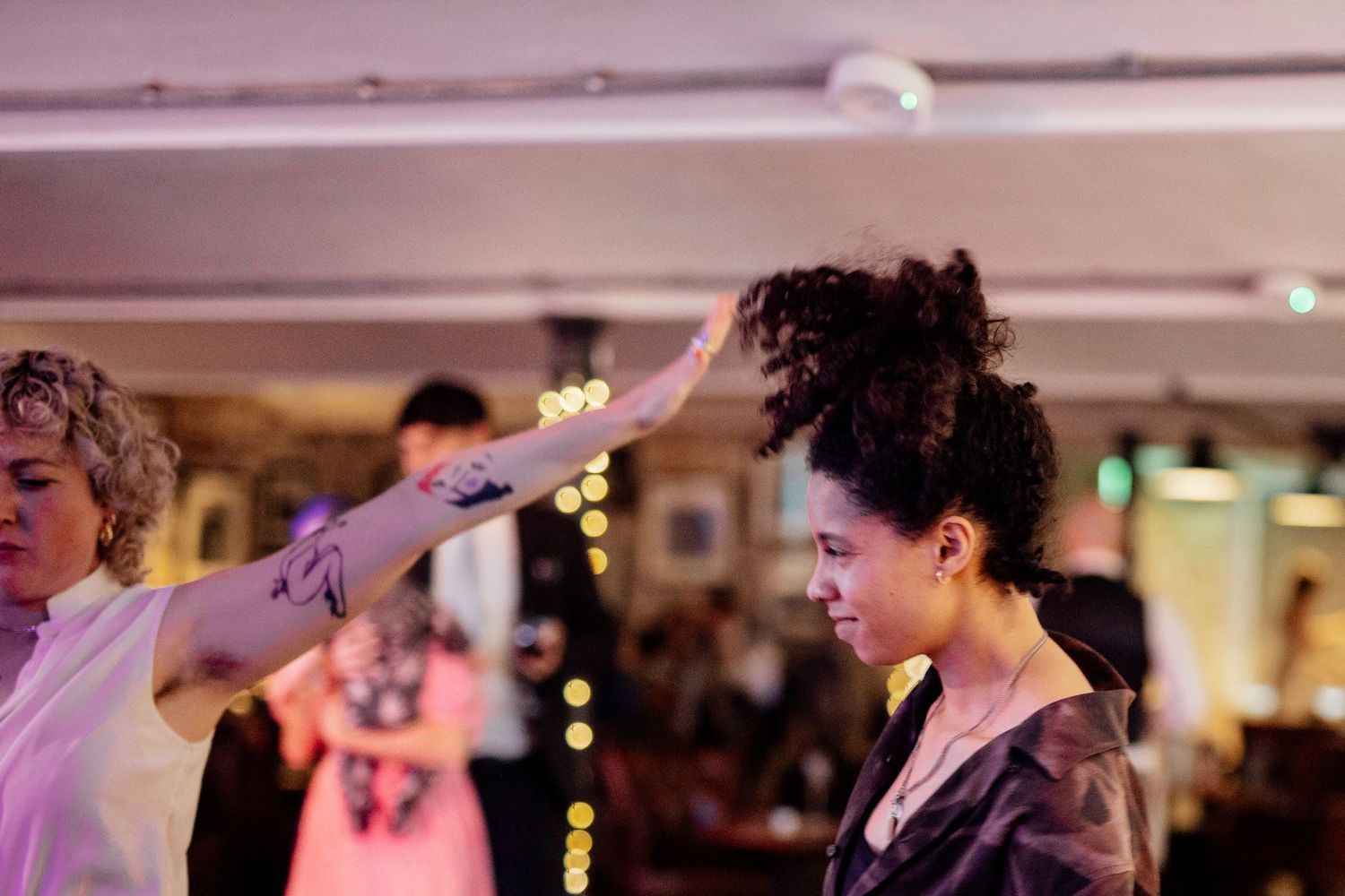 Wedding guests dancing and celebrating on a purple-lit dance floor.