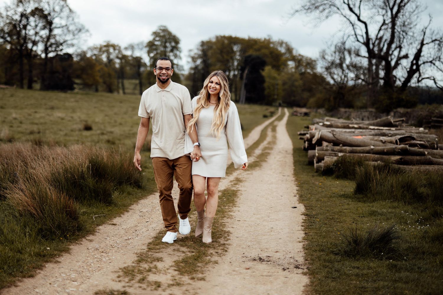 A family walks together along a scenic countryside path wearing matching neutral-toned outfits.