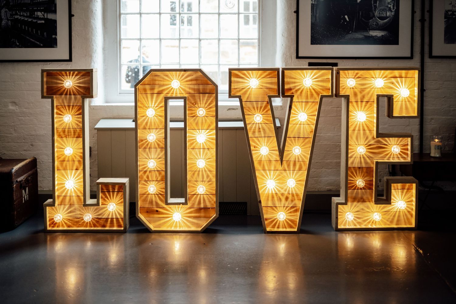 Illuminated marquee letters spelling 'LOVE' create a warm glowing display against a dark background.