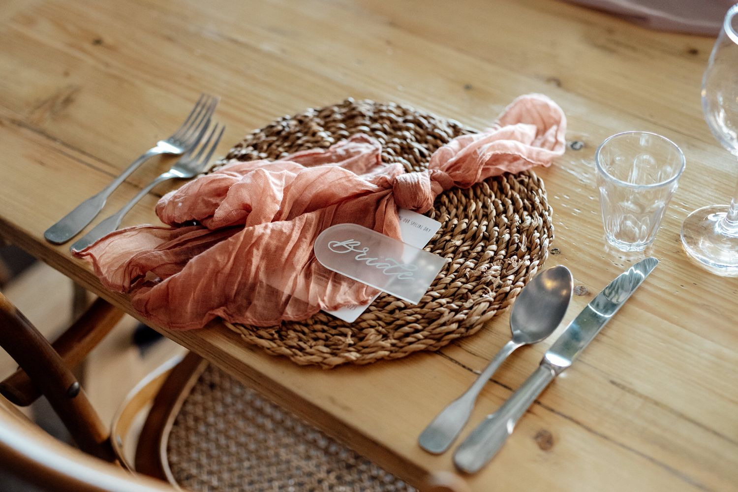 Place settings with woven placemats and silverware on wooden tables.