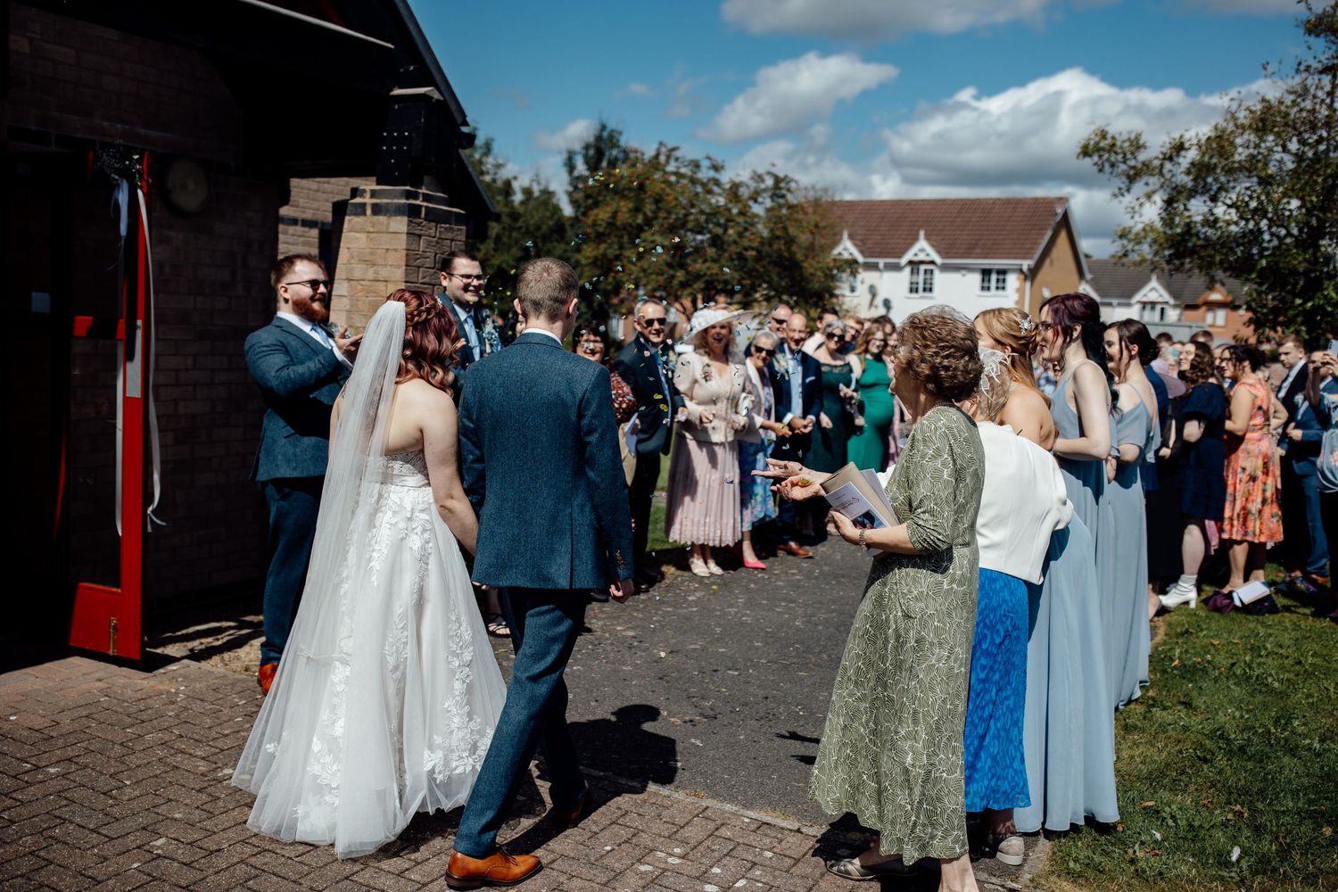 Wedding guests gathering outside a rustic venue on a sunny afternoon.
