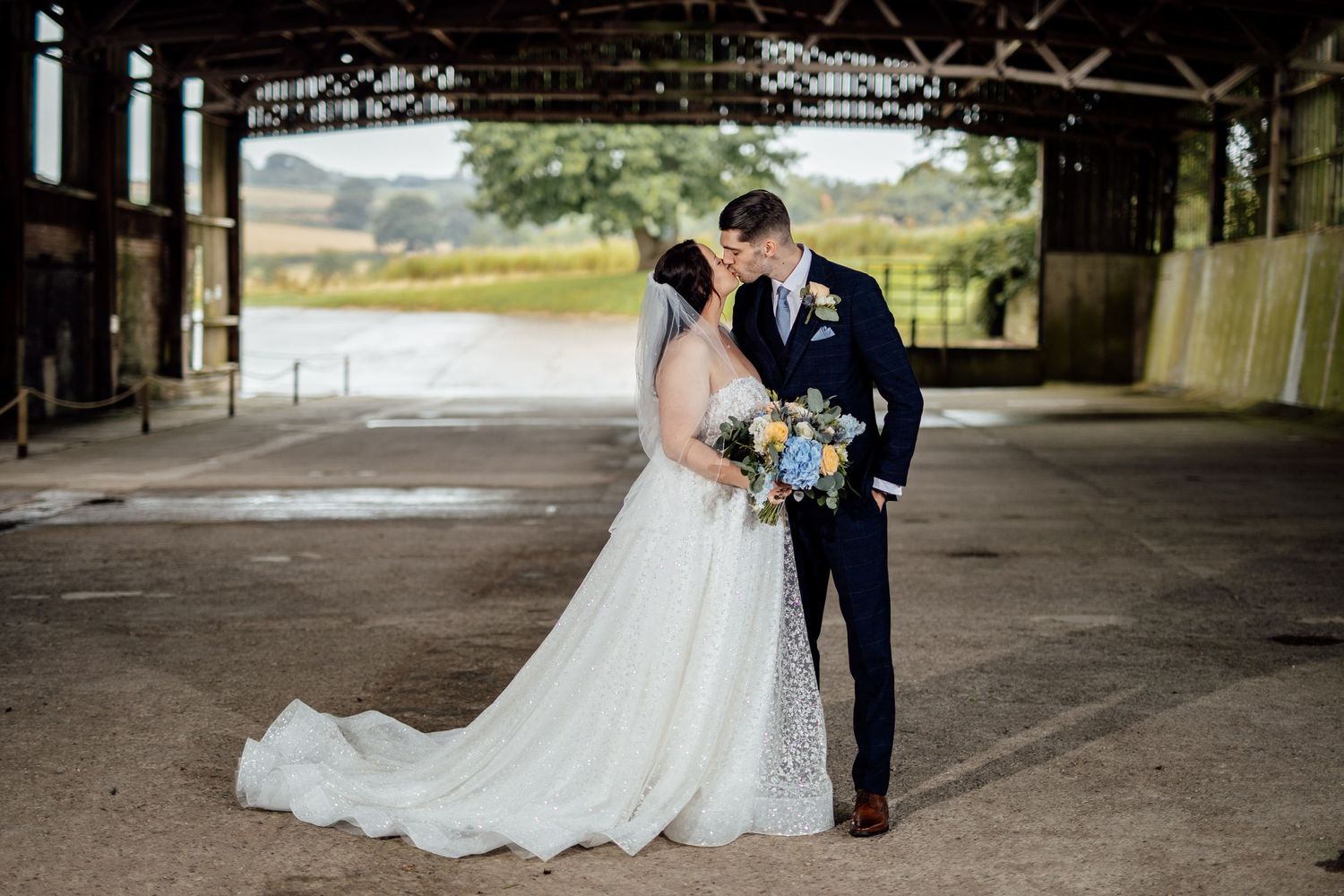 Bride and groom share intimate moment under covered rustic venue.