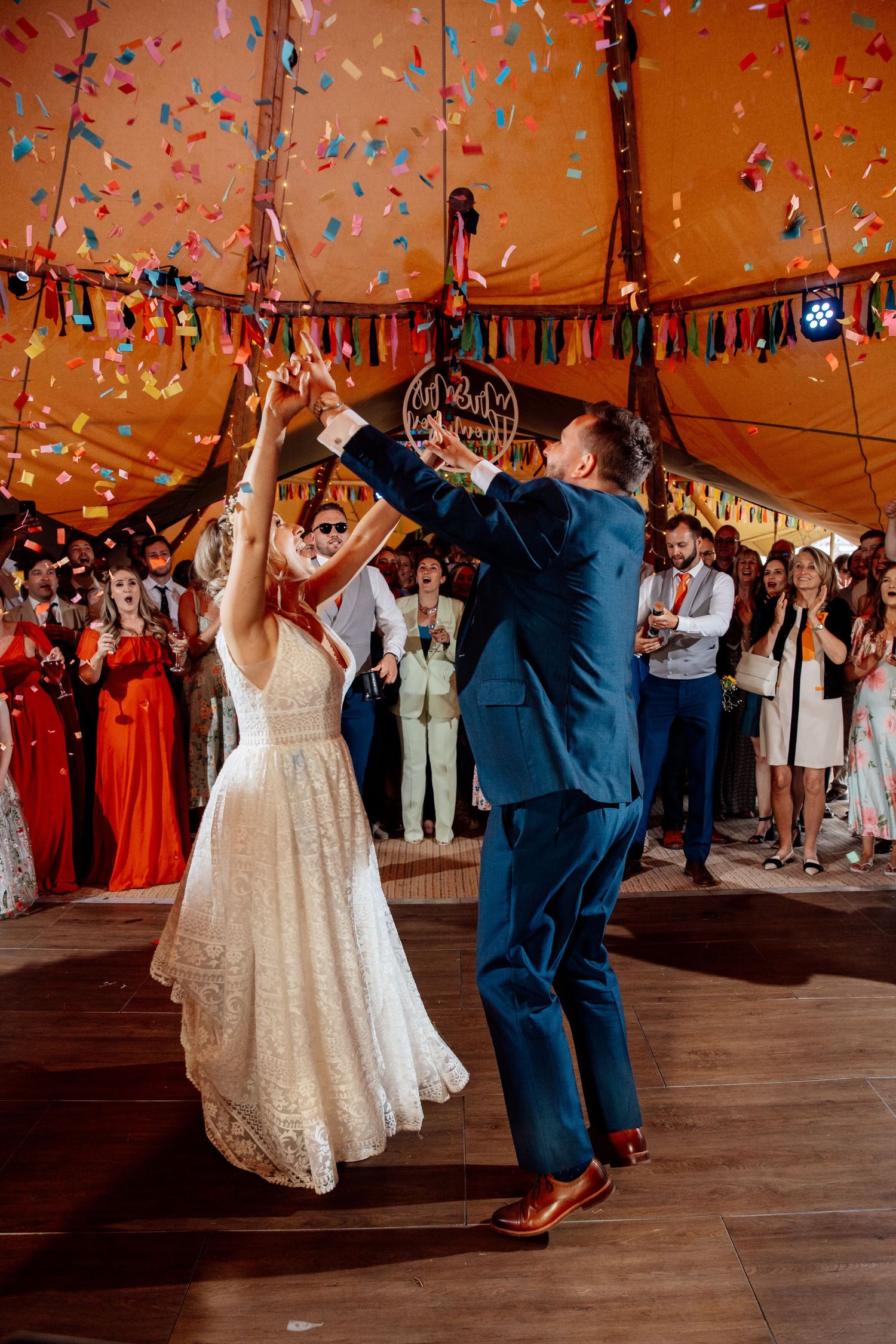 Couple dancing under colorful confetti and decorations at their wedding reception.