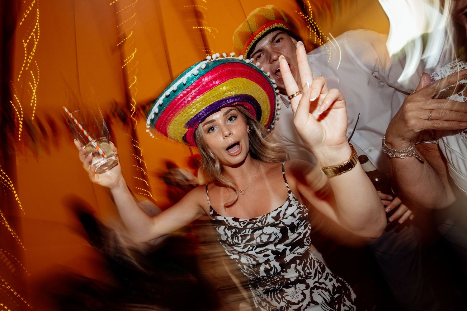Guests dancing and celebrating at a lively wedding party with colorful decorations.