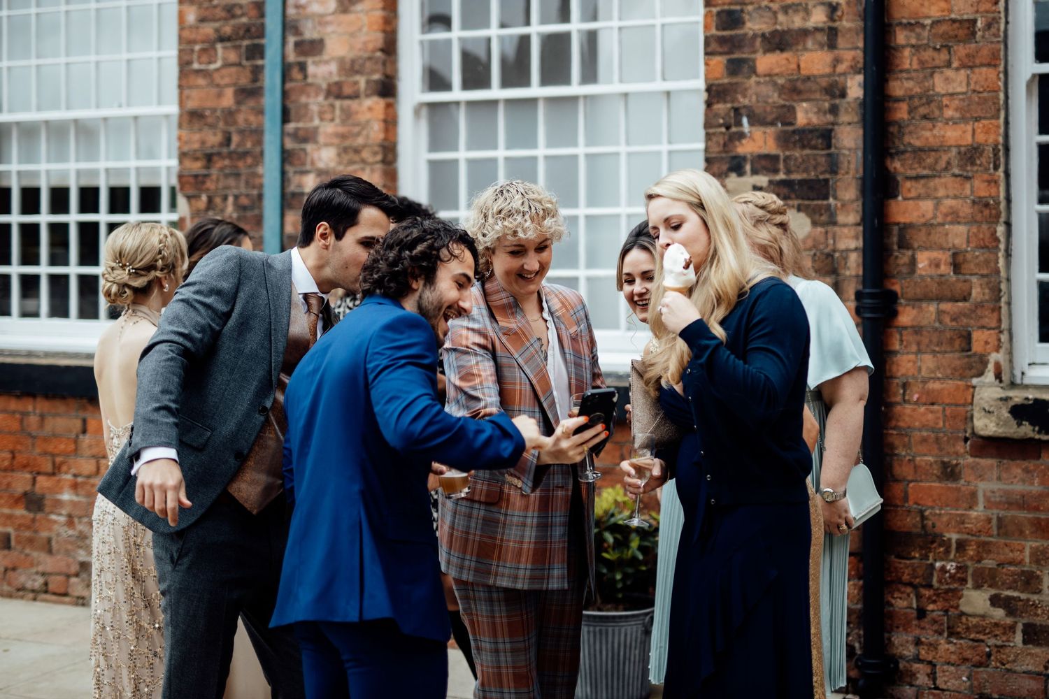 Group gathered outside a brick building sharing a moment together.