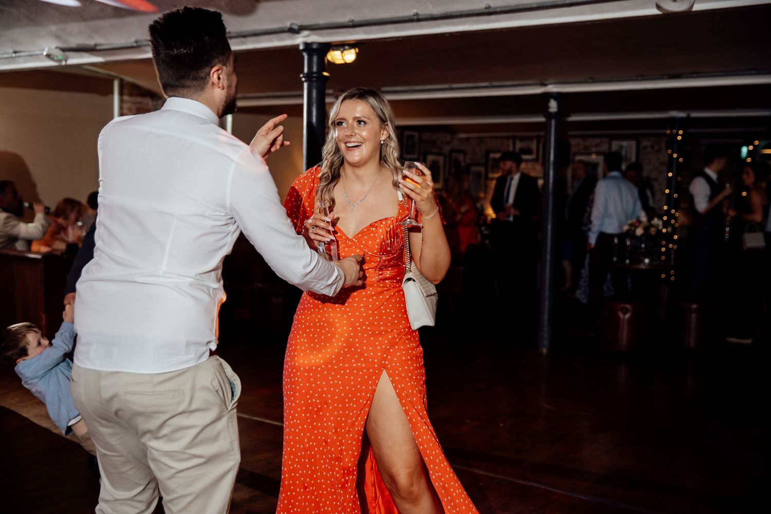 Wedding reception dance floor with guests dancing in a dimly lit venue.