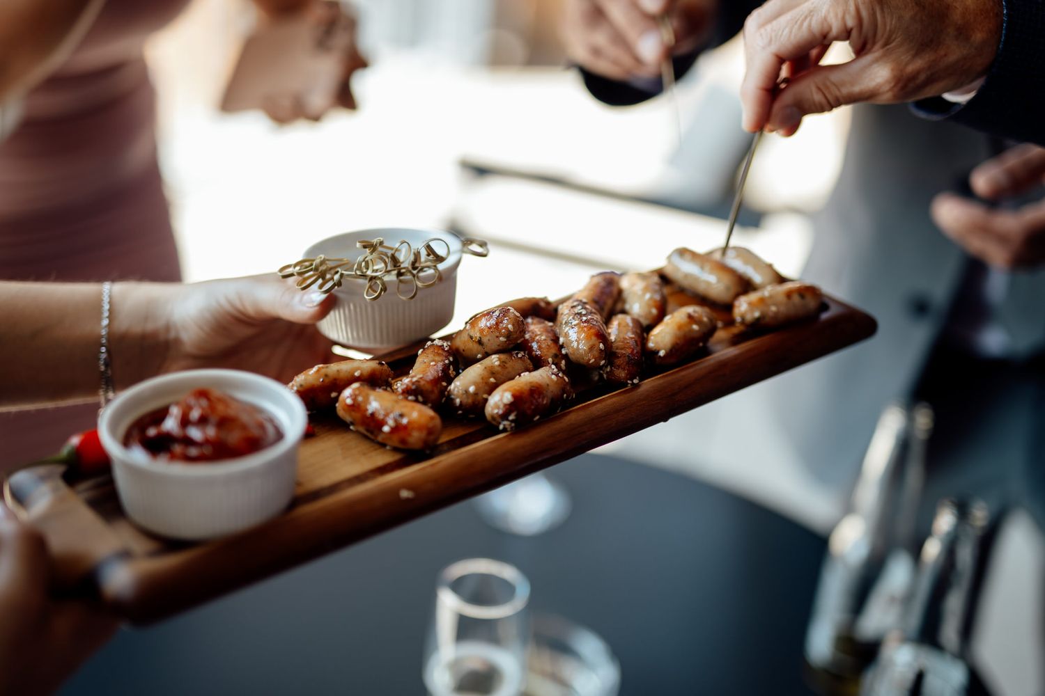 Appetizer board with chicken wings and dipping sauce being served at an event.