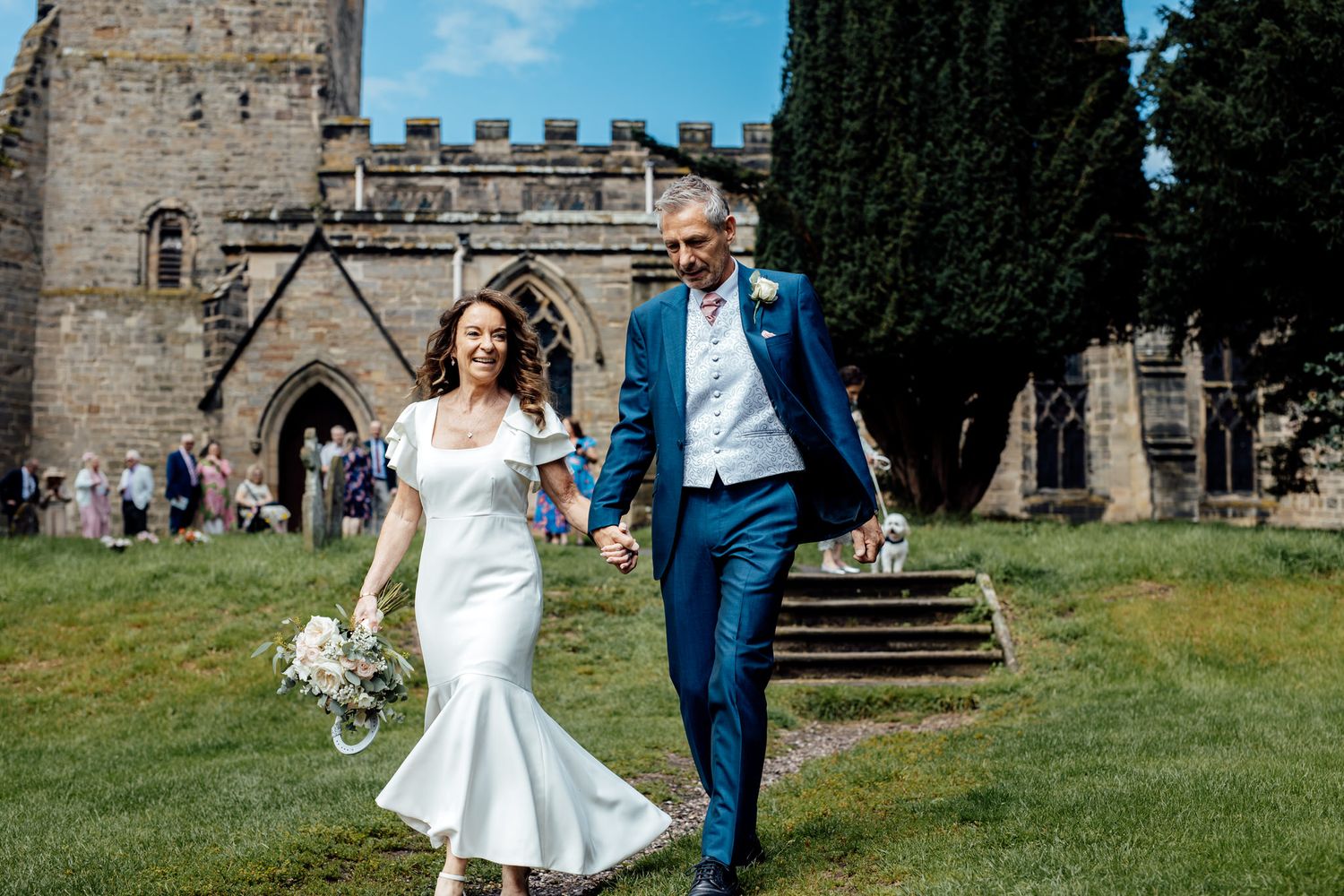 Wedding couple poses in front of historic stone building with rustic architecture.