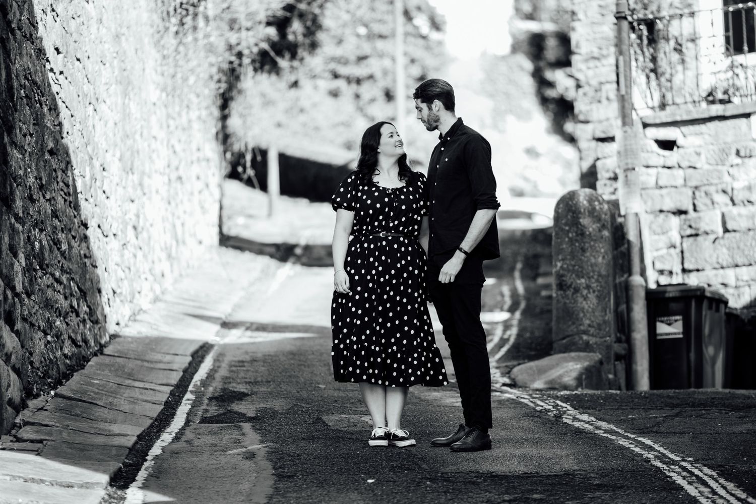 A black and white photo of a couple on a cobblestone street in vintage style.