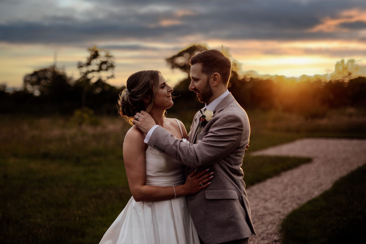Romantic sunset wedding portraits captured on a countryside path.