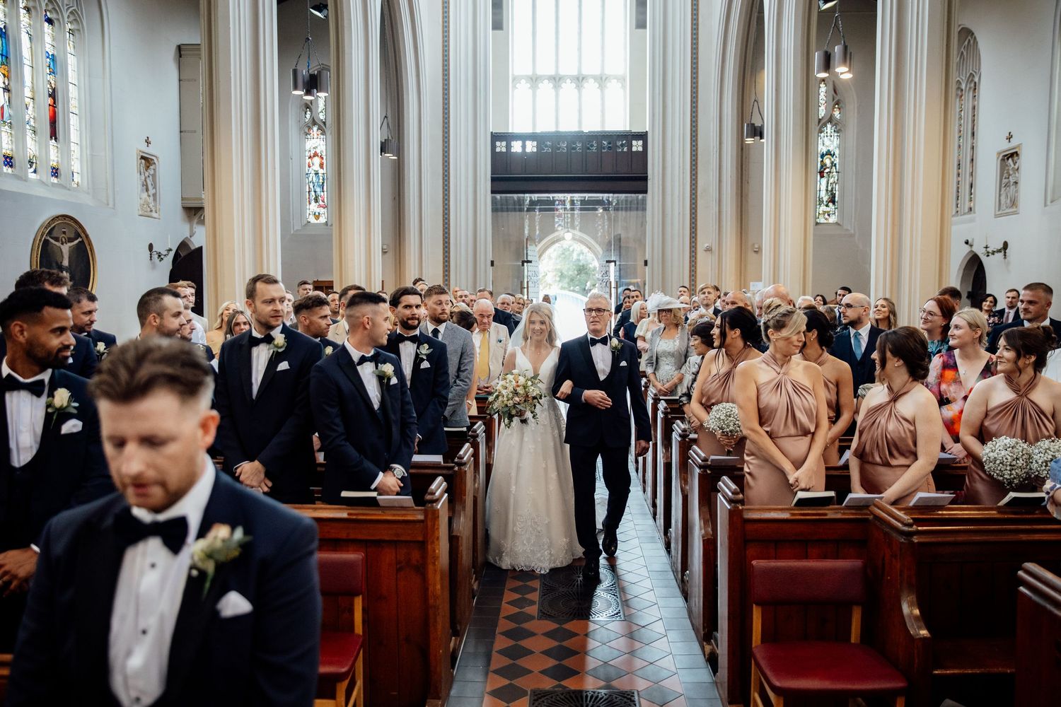Wedding ceremony in traditional church with guests seated in wooden pews.