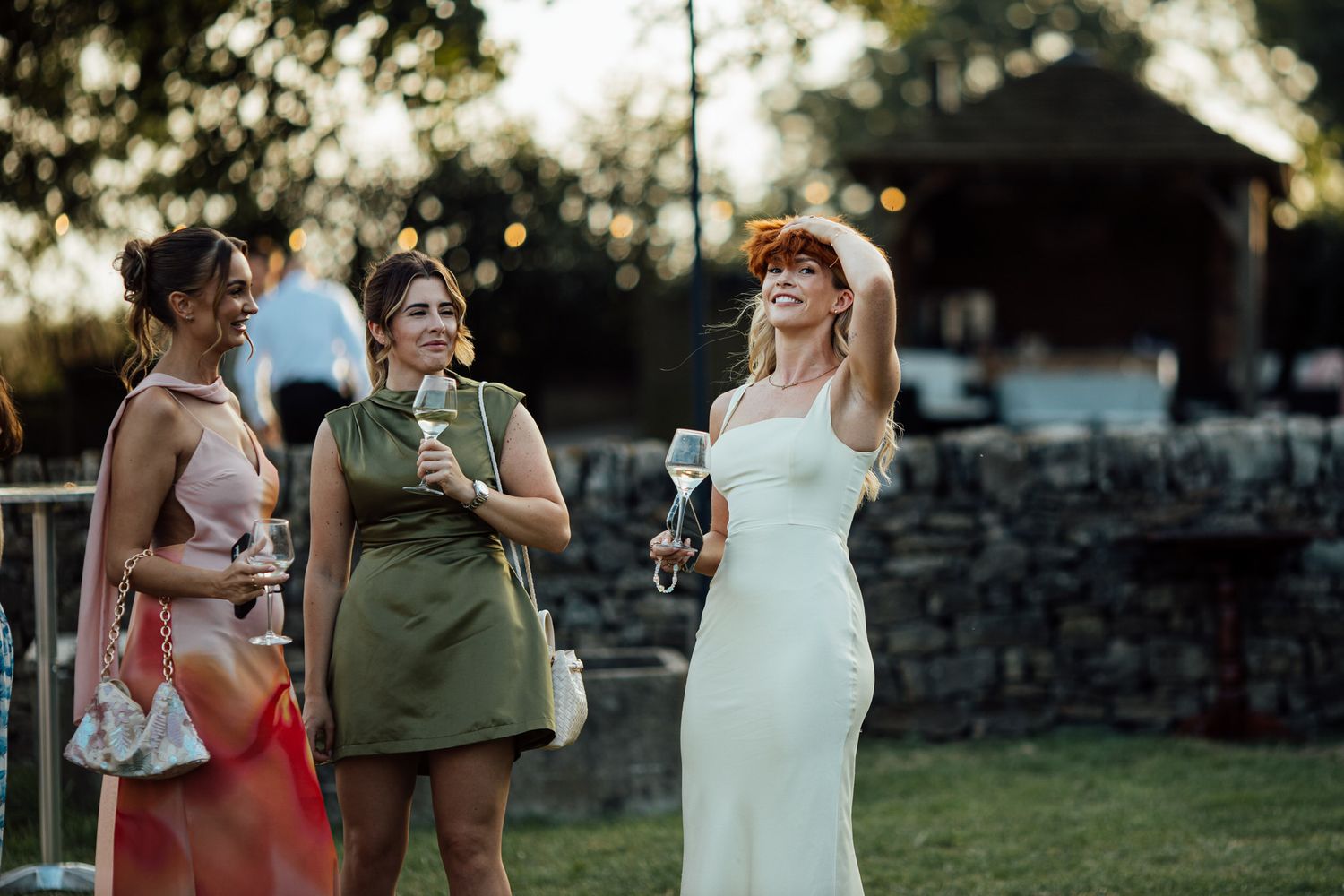Wedding guests enjoying drinks and conversation during an outdoor evening reception.