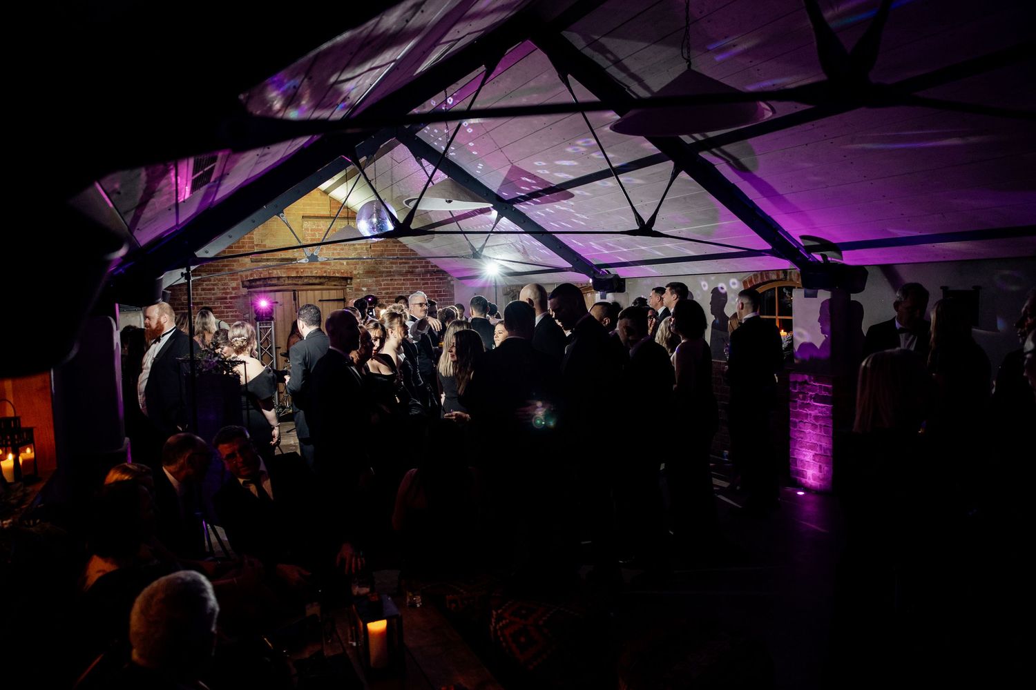 Wedding reception venue illuminated with purple uplighting creates a dramatic atmosphere.