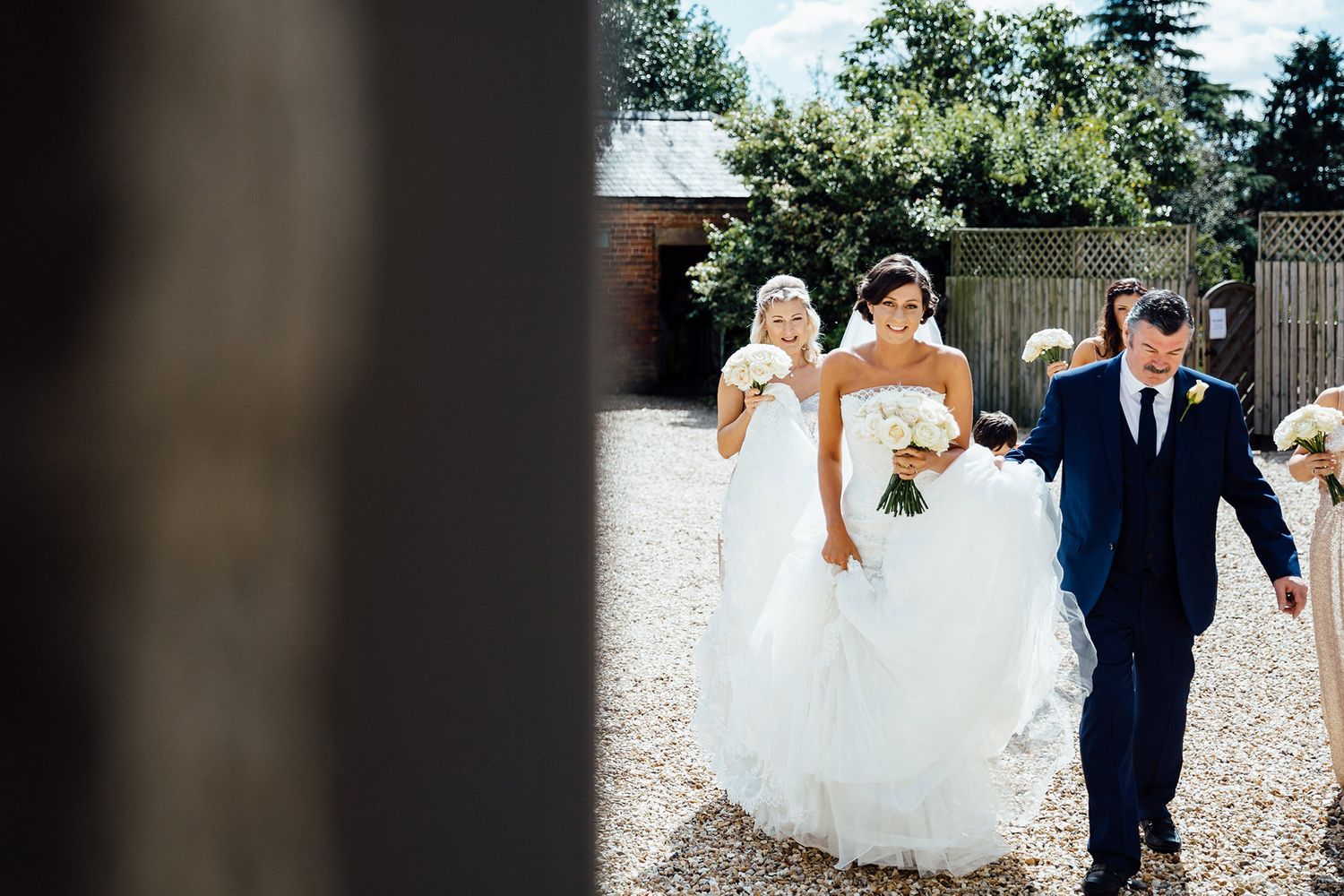 Wedding party walking together on a gravel path surrounded by greenery.