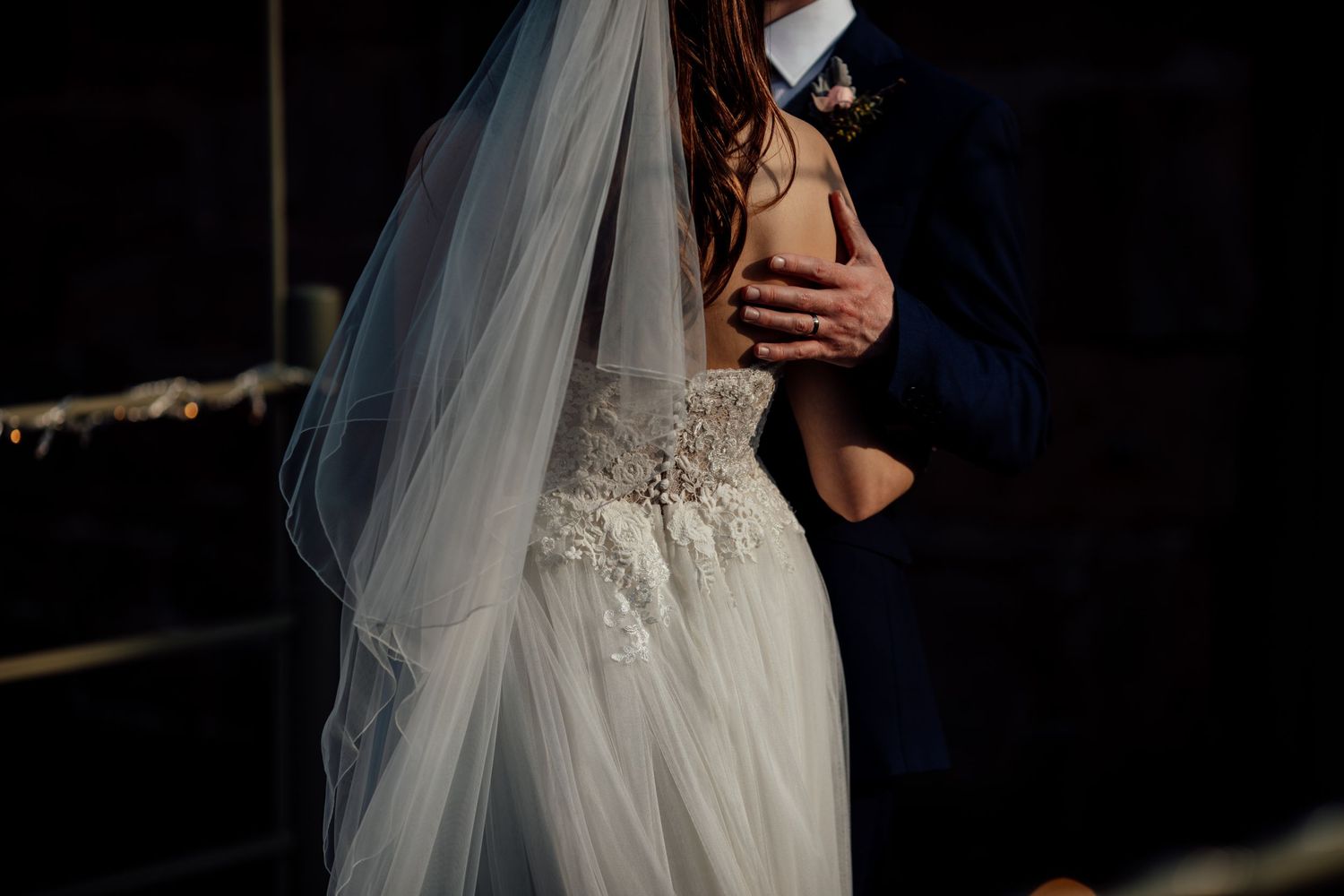 Intimate wedding moments captured in dramatic low-light setting with flowing white dress.
