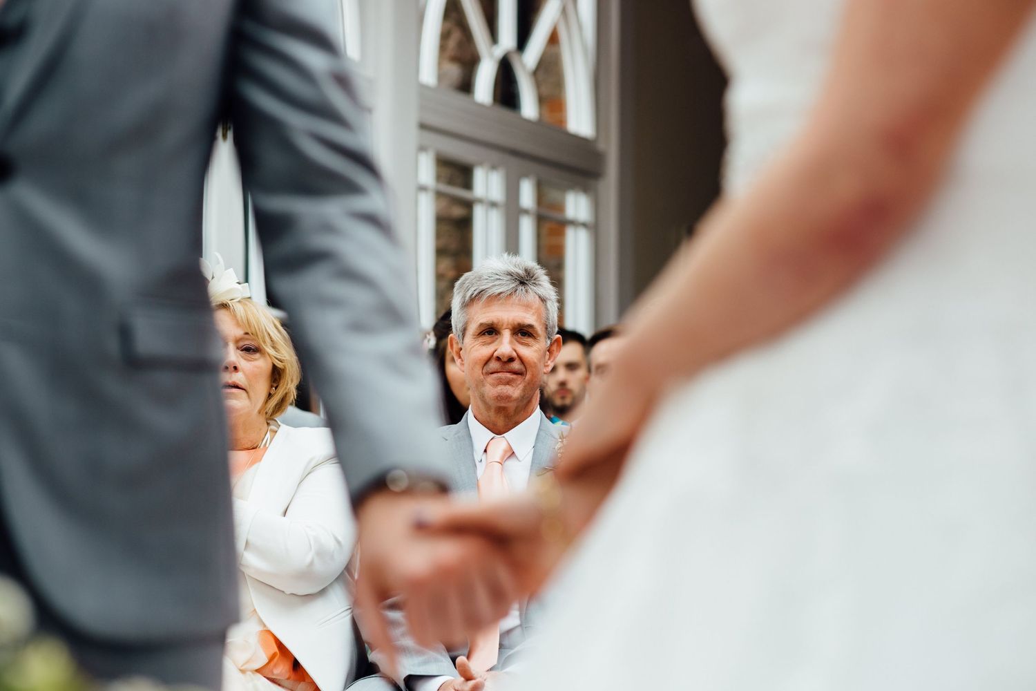 Wedding guests react with joy and emotion during an indoor ceremony.