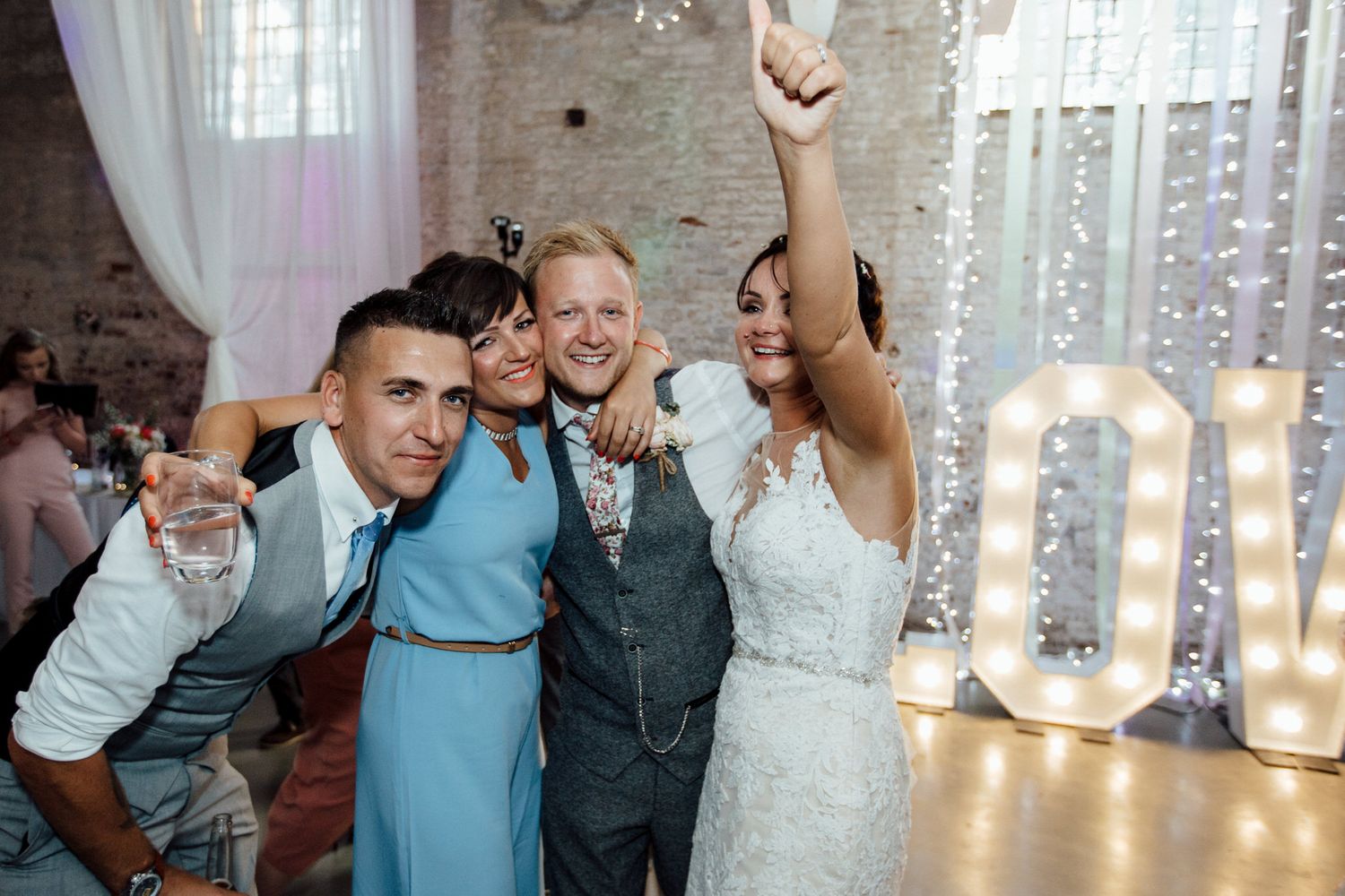 Wedding celebration with string lights and exposed brick wall backdrop.