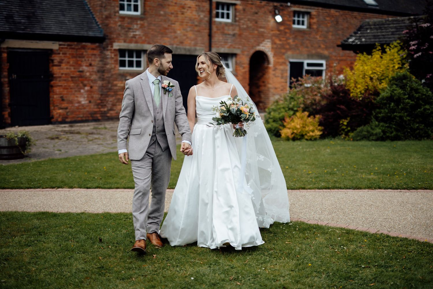 Wedding party photos outside a charming brick building with autumn foliage.