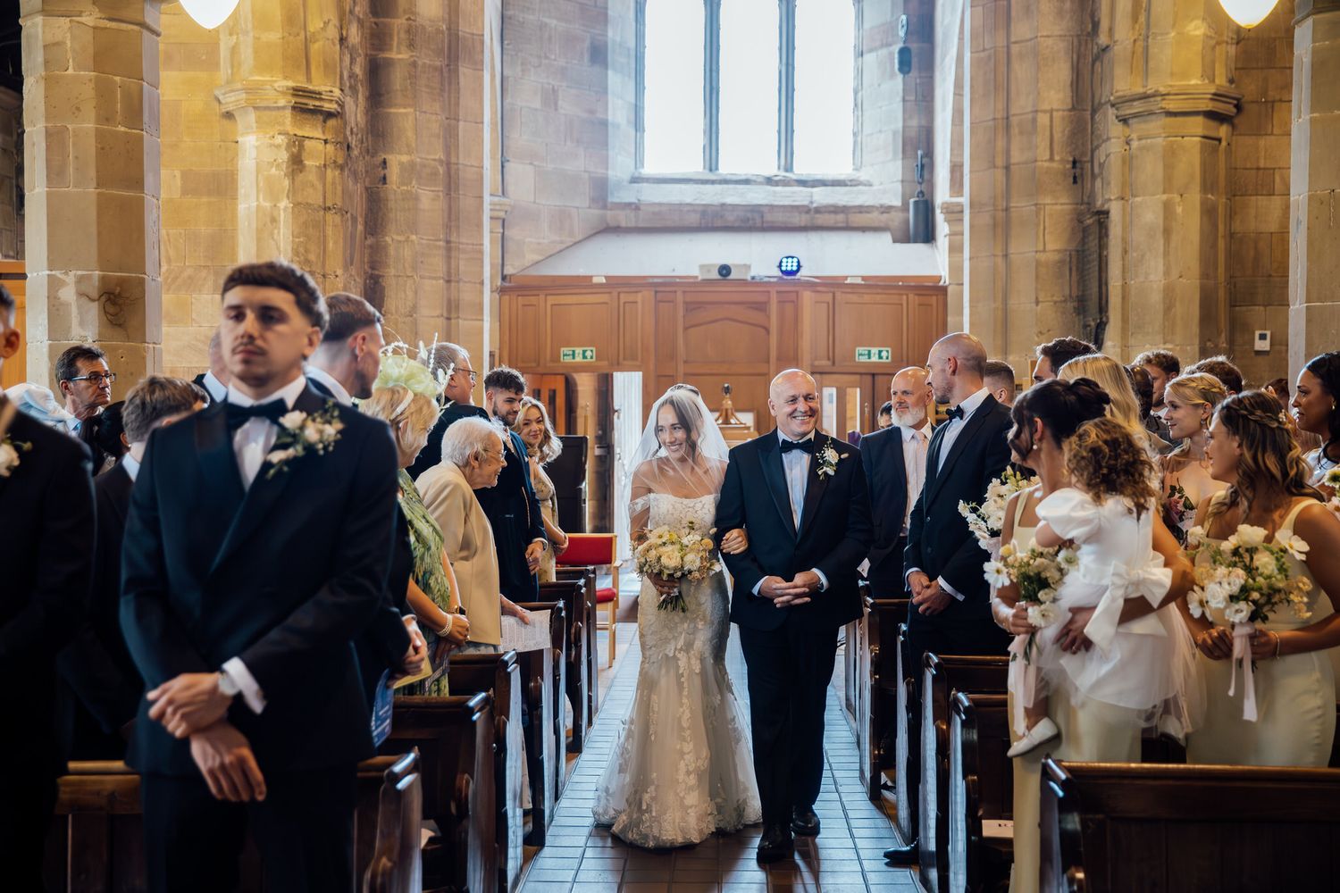 Gothic church interior with high ceilings and wooden pews during wedding ceremony.