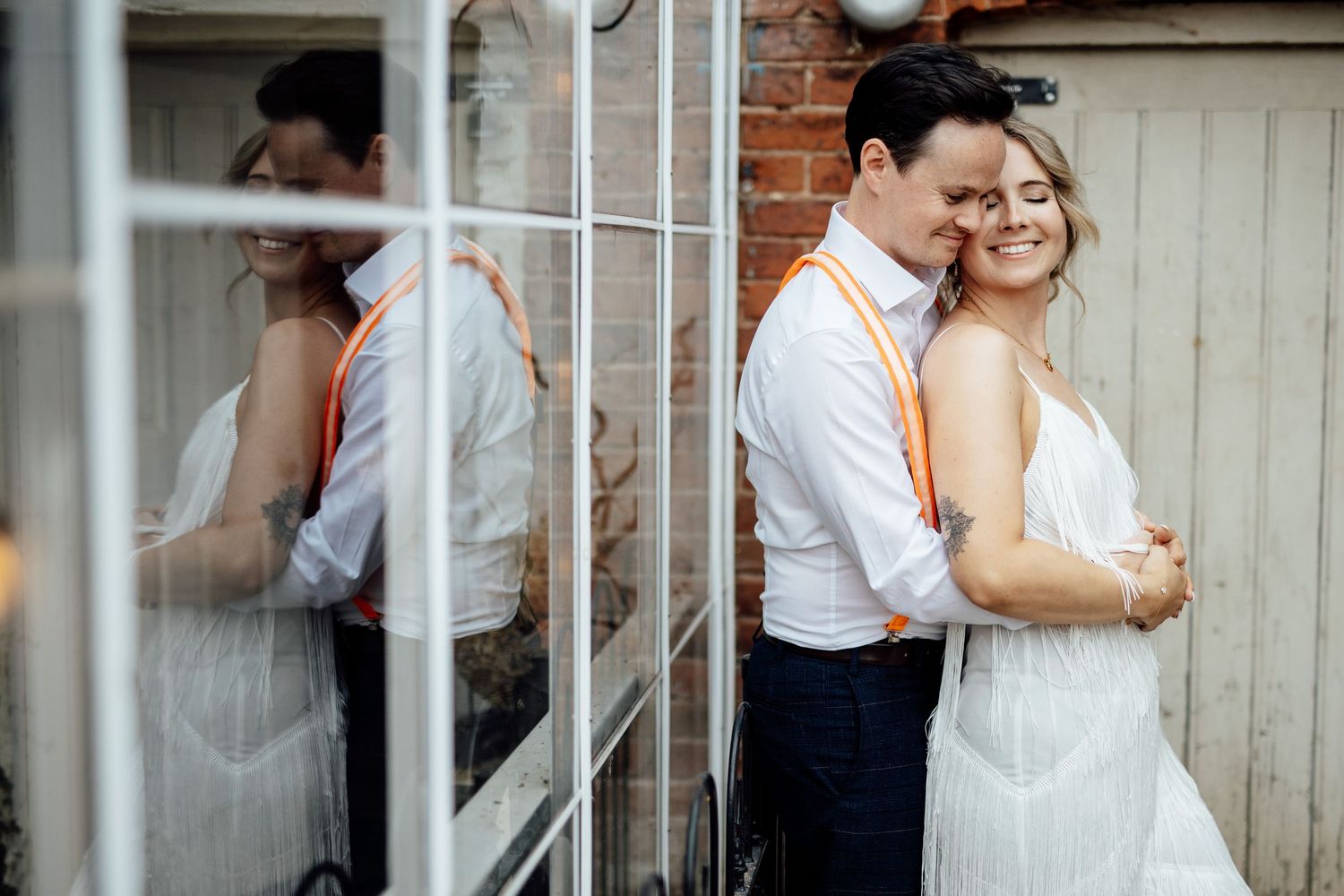 A couple shares an intimate moment behind white railings on their wedding day.