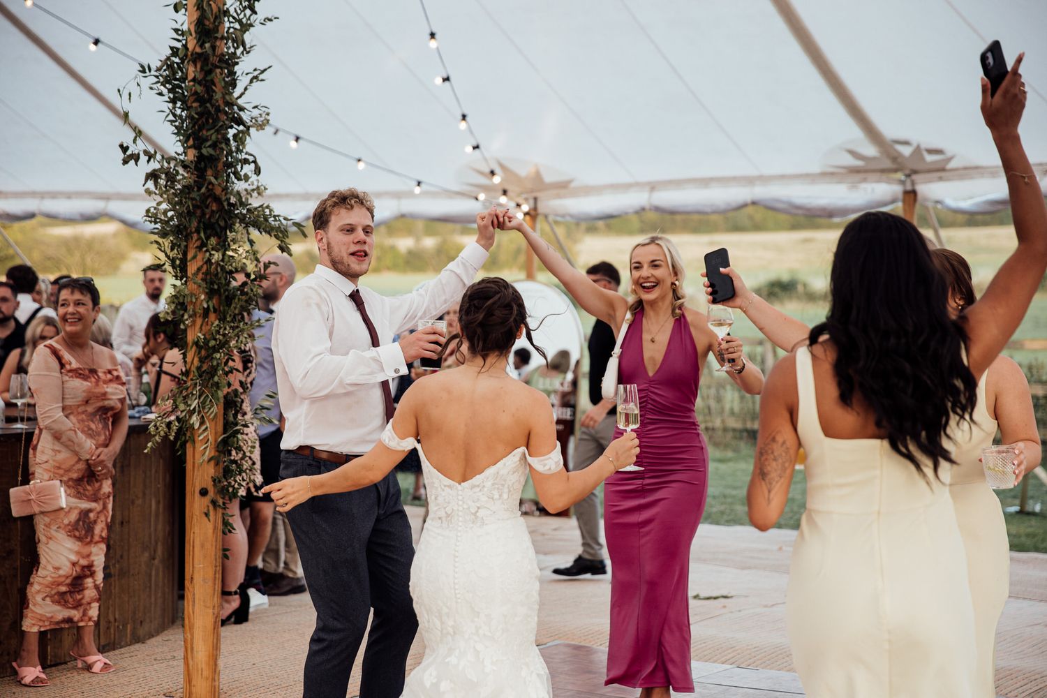 Wedding celebration under white tent with guests dancing and celebrating on the dance floor.
