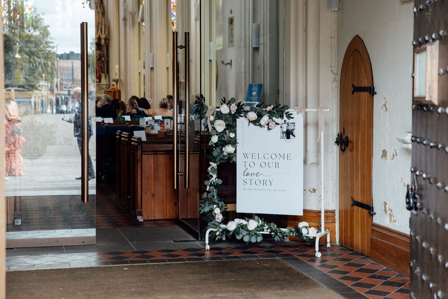 Church entrance hall decorated with fairy lights and white floral arrangements.