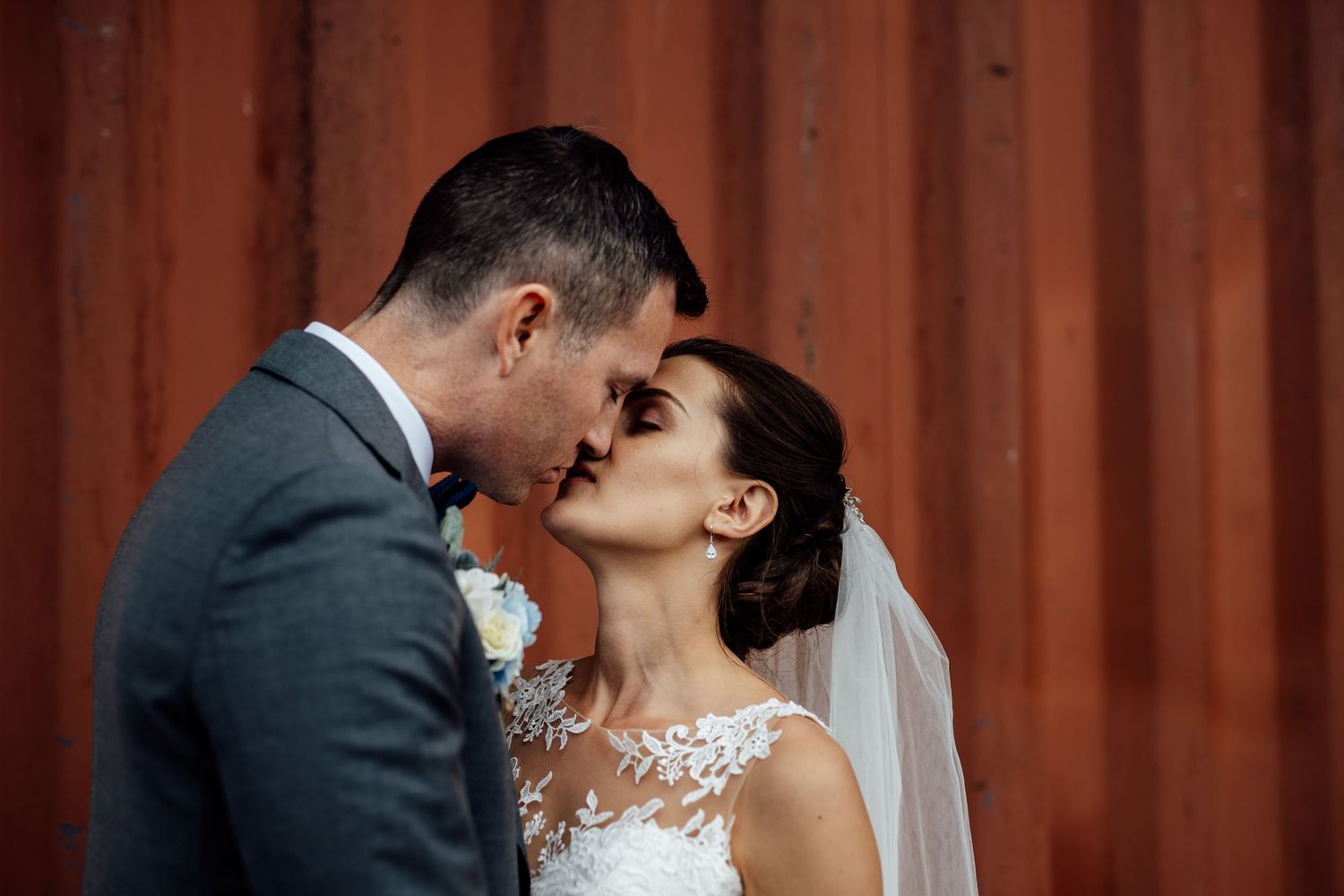 Elegant wedding ceremony moment in front of a wooden fence backdrop.