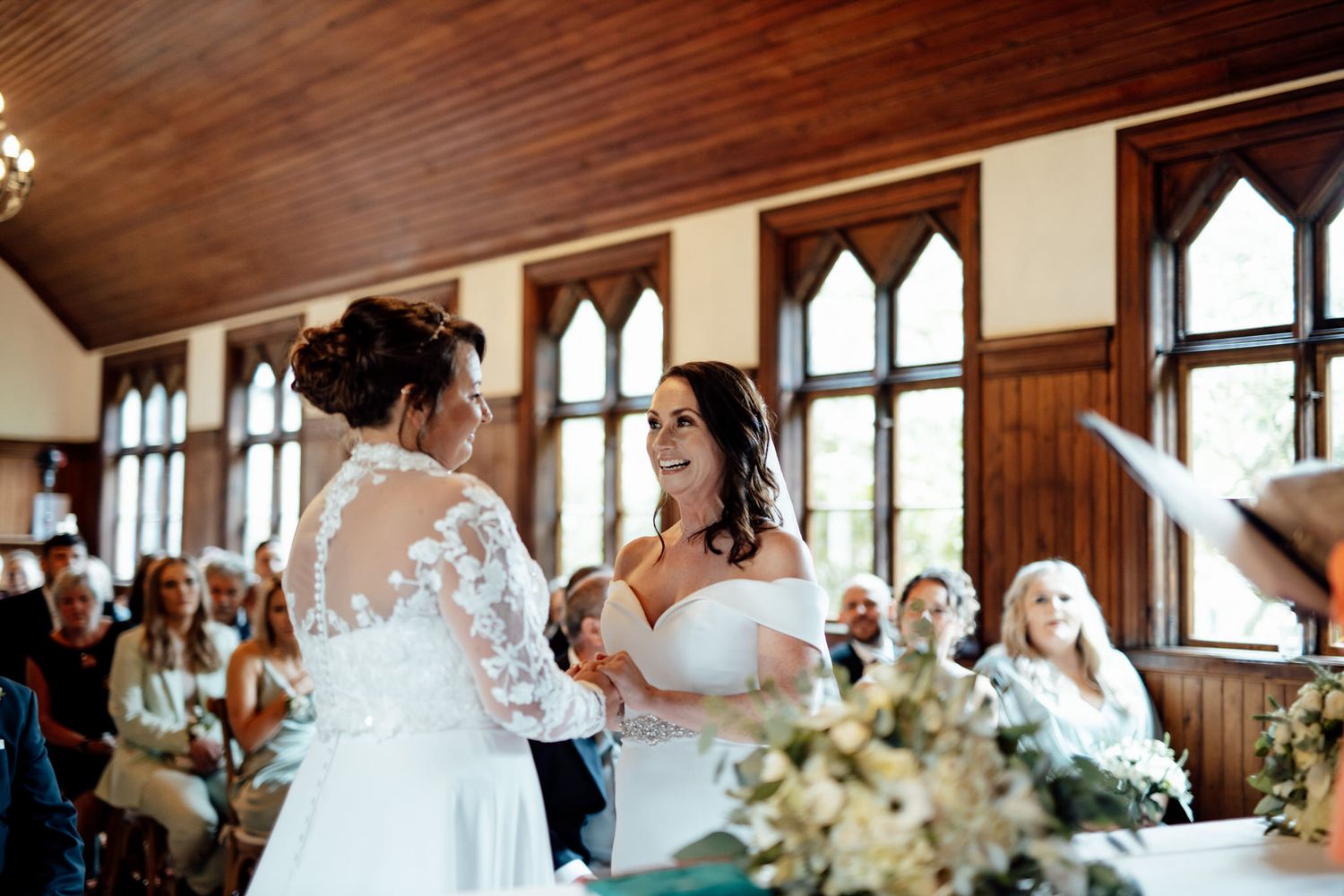 Intimate wedding ceremony moment in a chapel with gothic windows and wooden details.