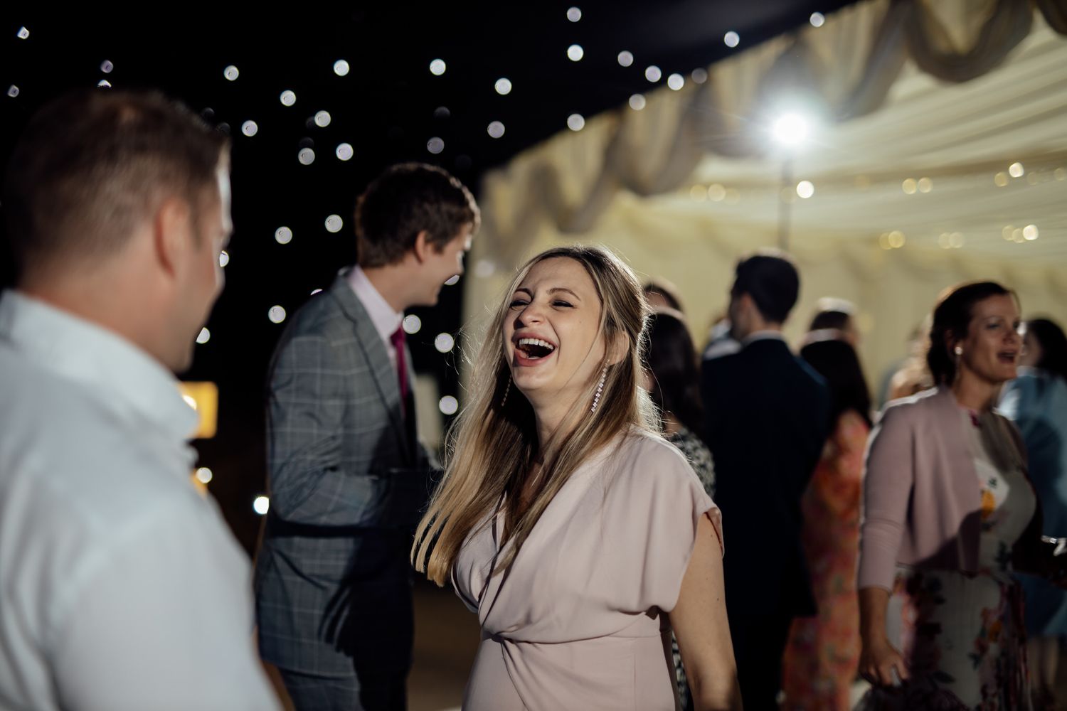Wedding guests enjoying themselves on a lively dance floor with festive lighting.