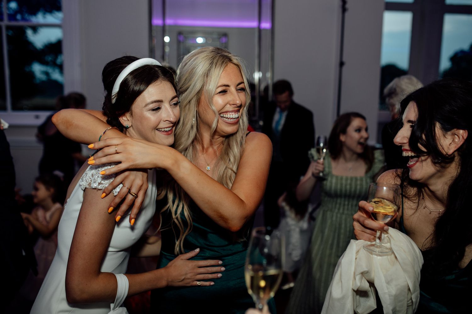 Wedding reception party with guests dancing and celebrating under atmospheric lighting.