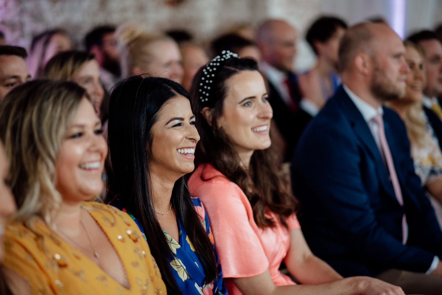 Wedding guests seated in colorful attire watching ceremony proceedings.