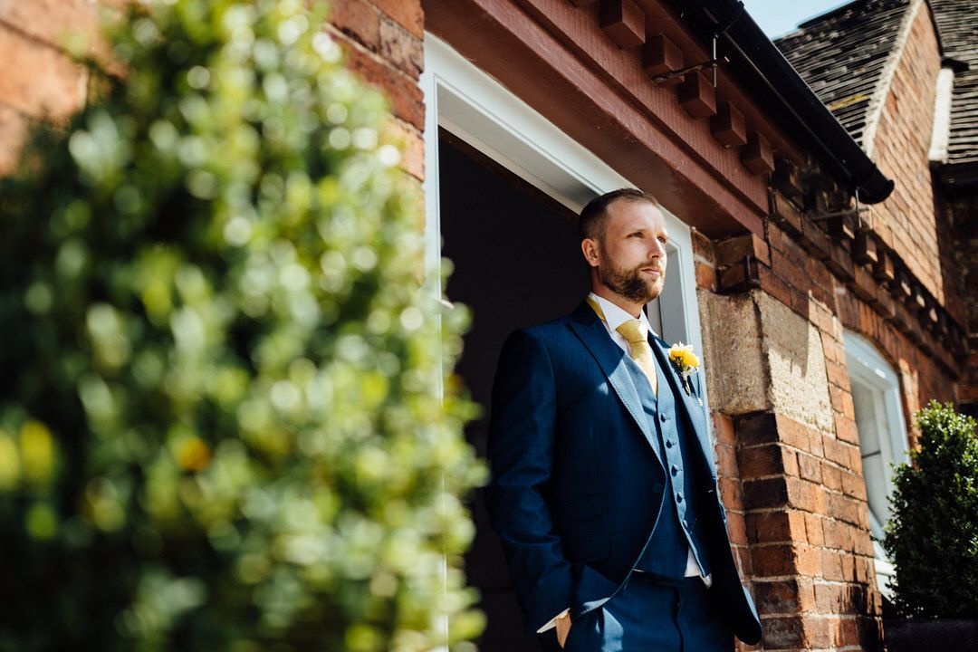 Wedding party members standing outside a rustic brick building in formal attire.