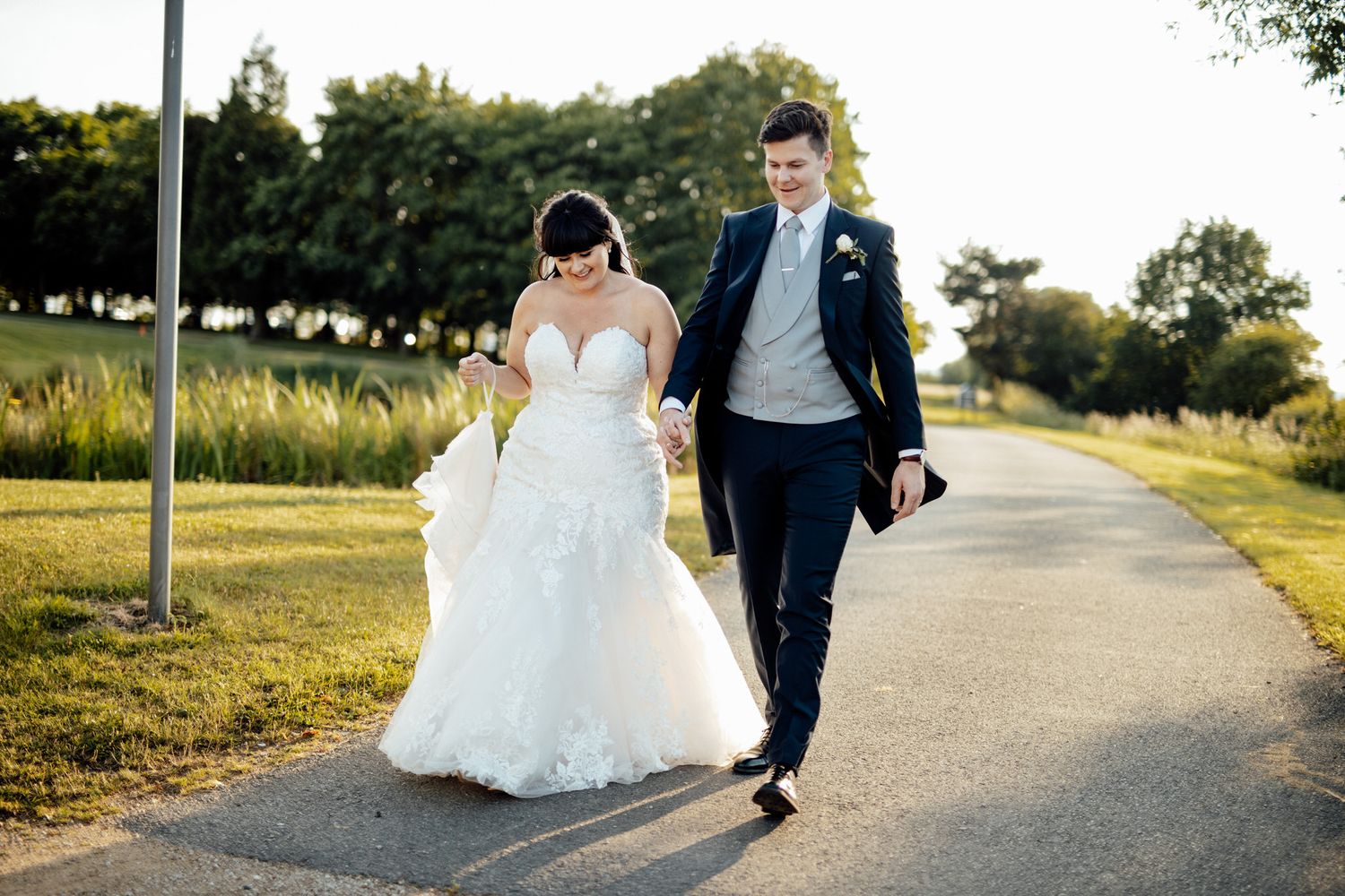 Couple walking together on a sunlit path during golden hour.