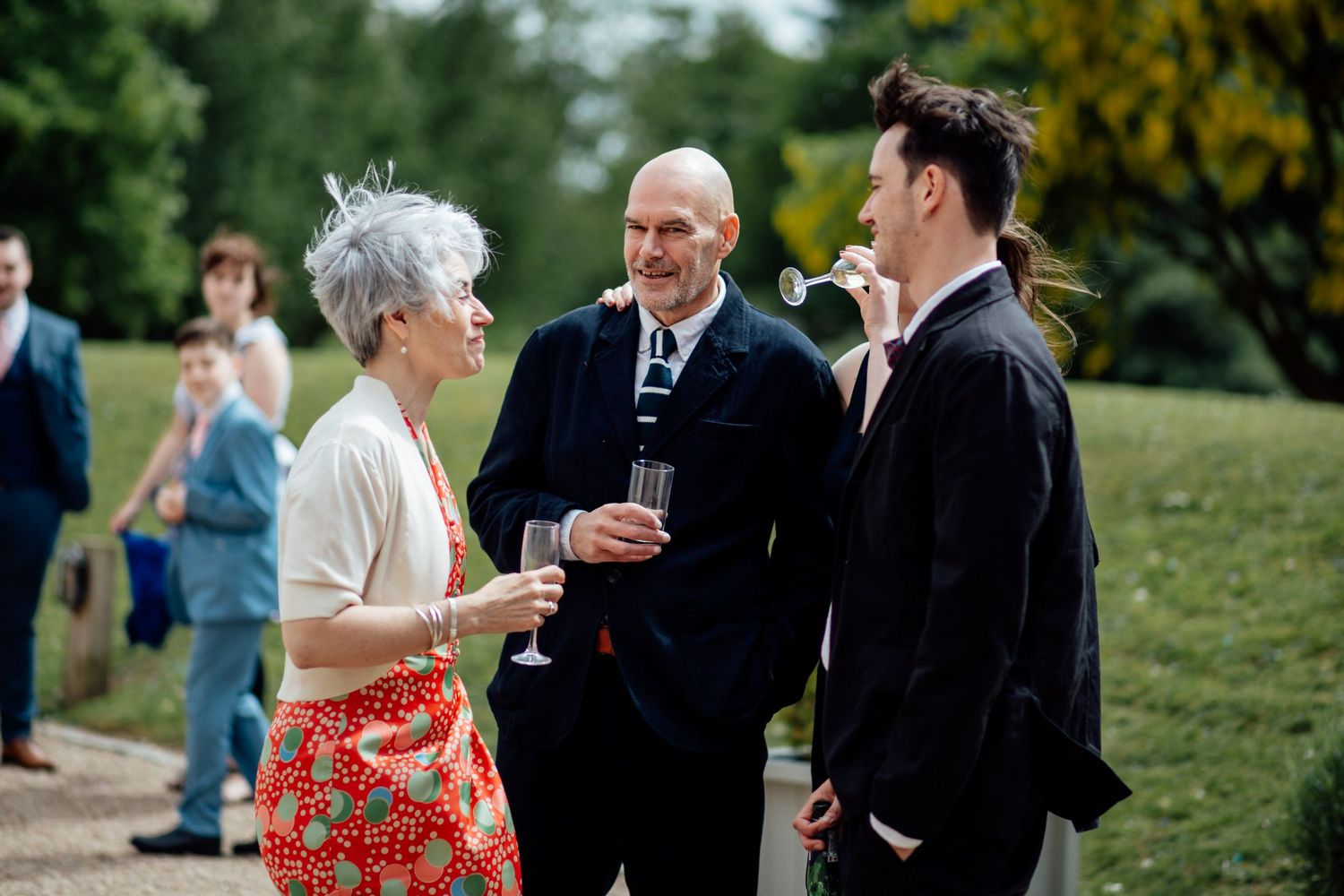 Wedding guests mingling on a grassy lawn during an outdoor reception.
