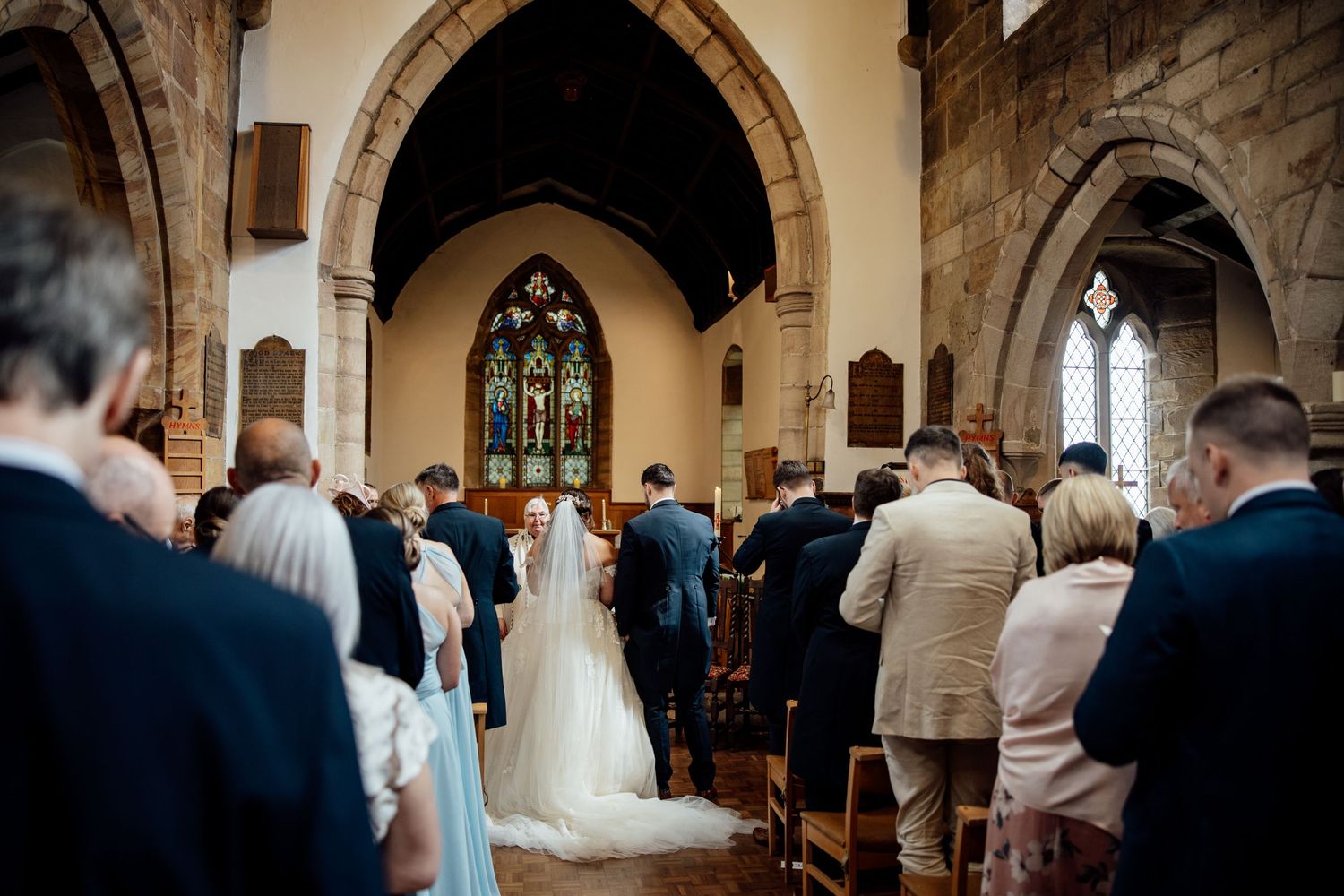 Wedding ceremony in traditional church with gothic arches and stained glass windows.