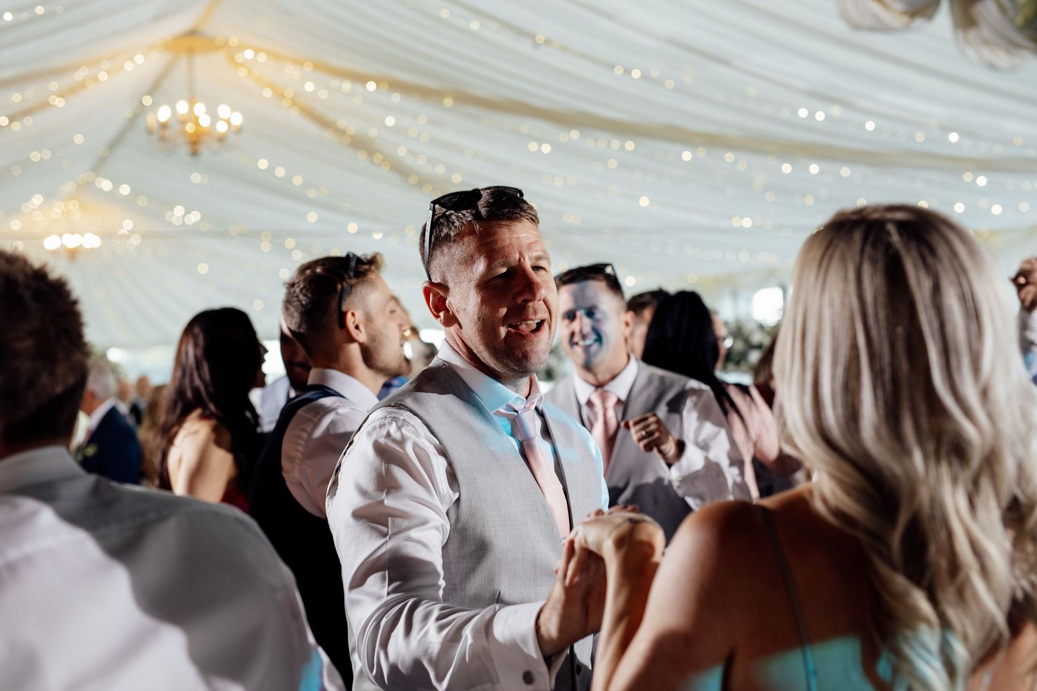 Wedding reception celebration under twinkling lights in elegant indoor venue.
