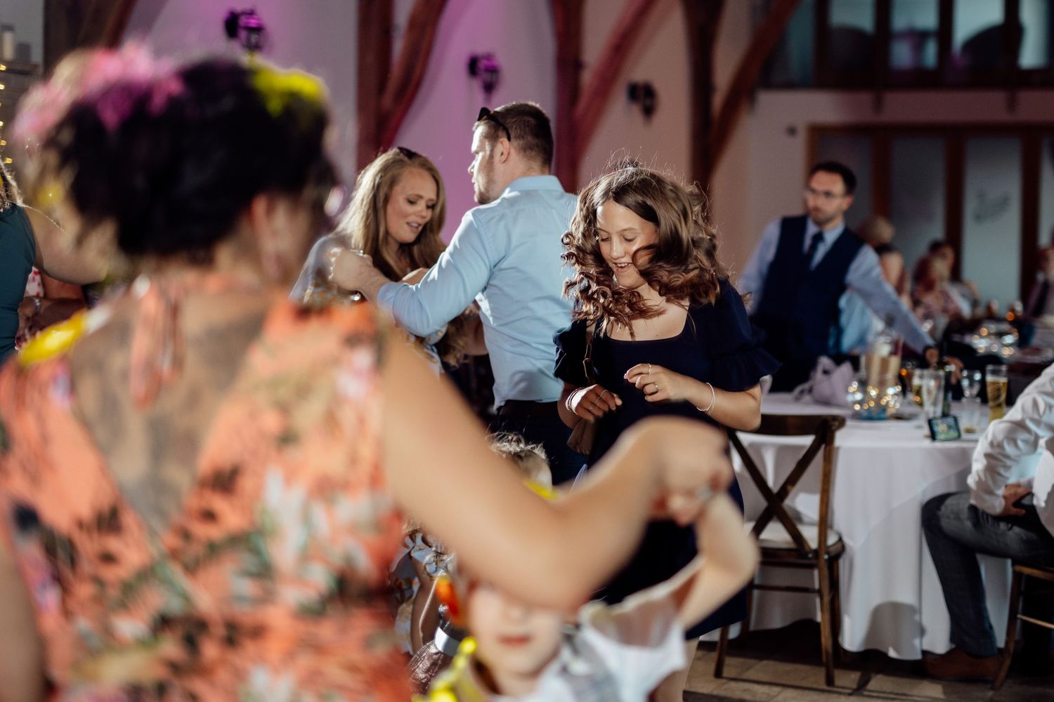 Wedding reception venue decorated with colorful lighting and floral arrangements.