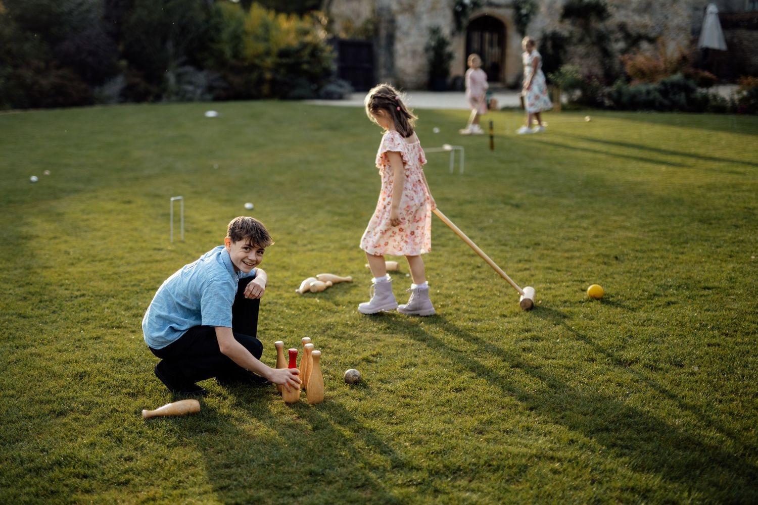 Children playing lawn games outdoors during a wedding reception at sunset.