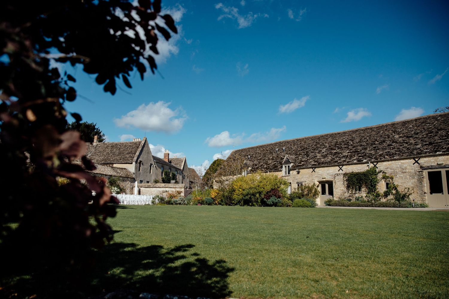 Panoramic view of a rustic stone wedding venue with rolling green hills and blue sky.