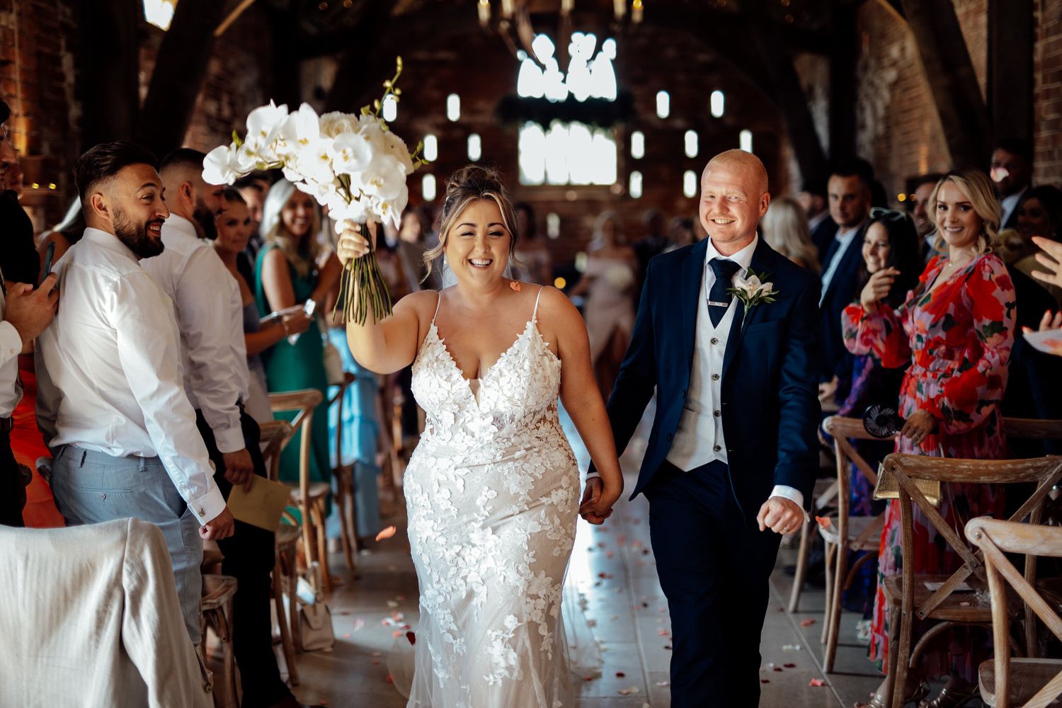 Wedding celebration in rustic venue with guests dancing and enjoying festivities.